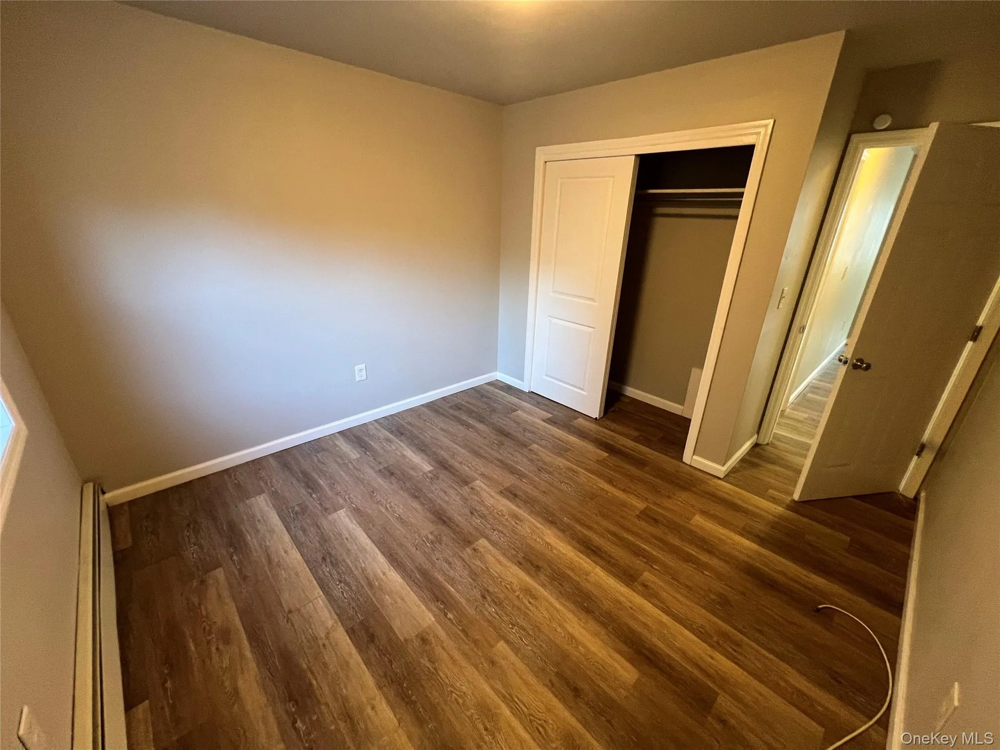 Wood-finish flooring throughout, neutral wall paint, and a closet with bi-fold doors Wood-finish flooring throughout, neutral wall paint, and a closet with bi-fold doors
