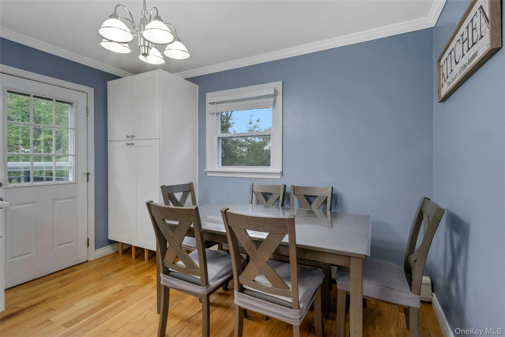 Wood-finish flooring, white built-in cabinetry, modern chandelier, white trim, and a transom-style door Wood-finish flooring, white built-in cabinetry, modern chandelier, white trim, and a transom-style door