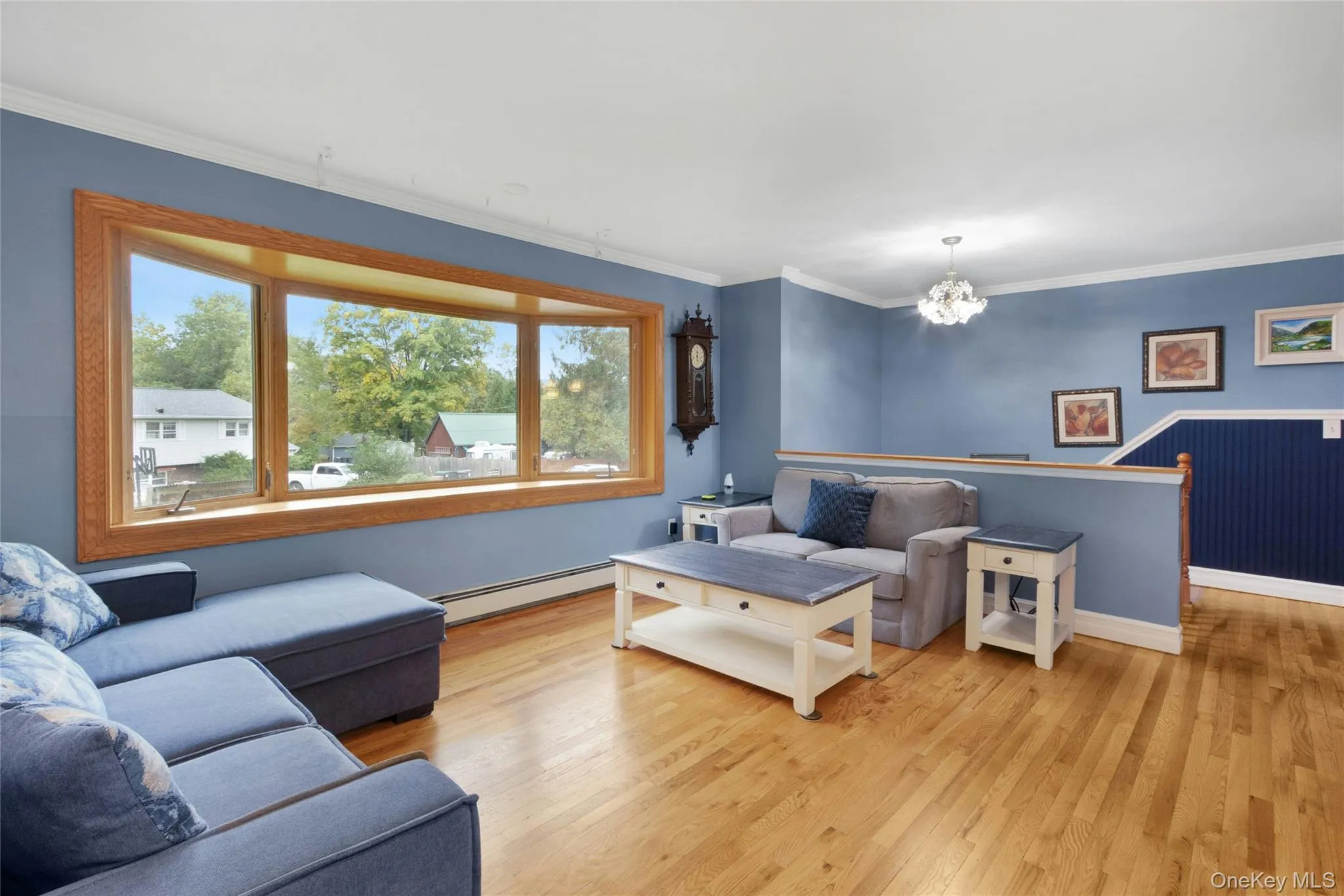 Expansive bay window with natural wood trim, hardwood flooring, crown molding, and a decorative chandelier Expansive bay window with natural wood trim, hardwood flooring, crown molding, and a decorative chandelier