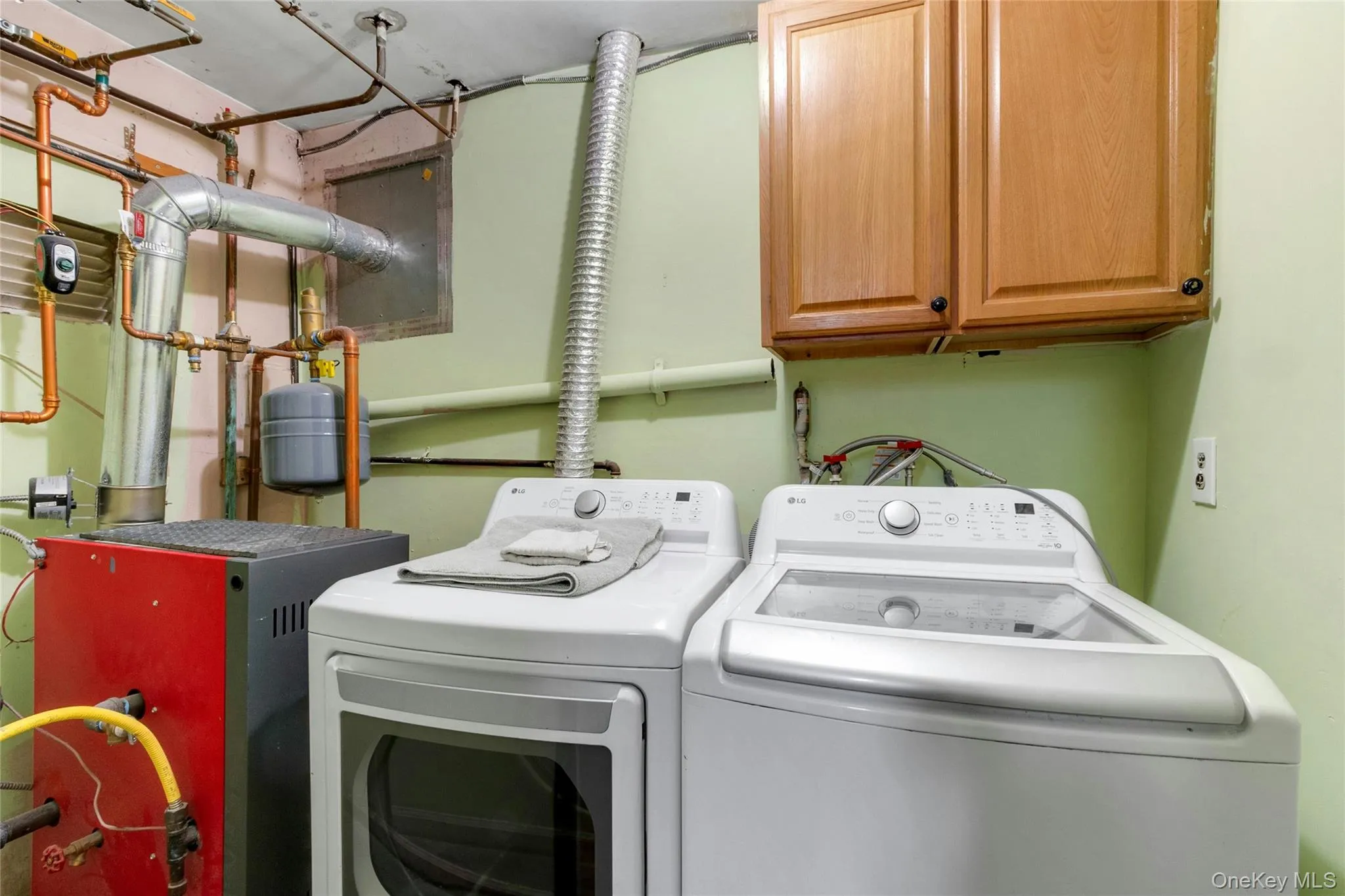 Utility area featuring overhead cabinetry, exposed copper piping, and a ventilation system Utility area featuring overhead cabinetry, exposed copper piping, and a ventilation system