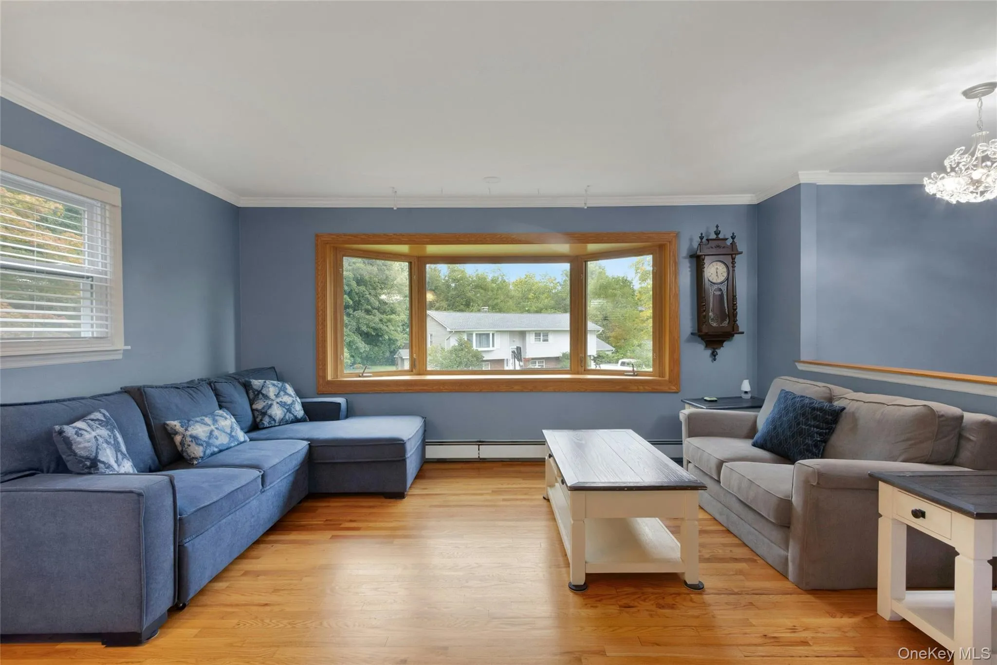 Hardwood flooring, bay window with wood trim, crown molding, and a decorative chandelier Hardwood flooring, bay window with wood trim, crown molding, and a decorative chandelier