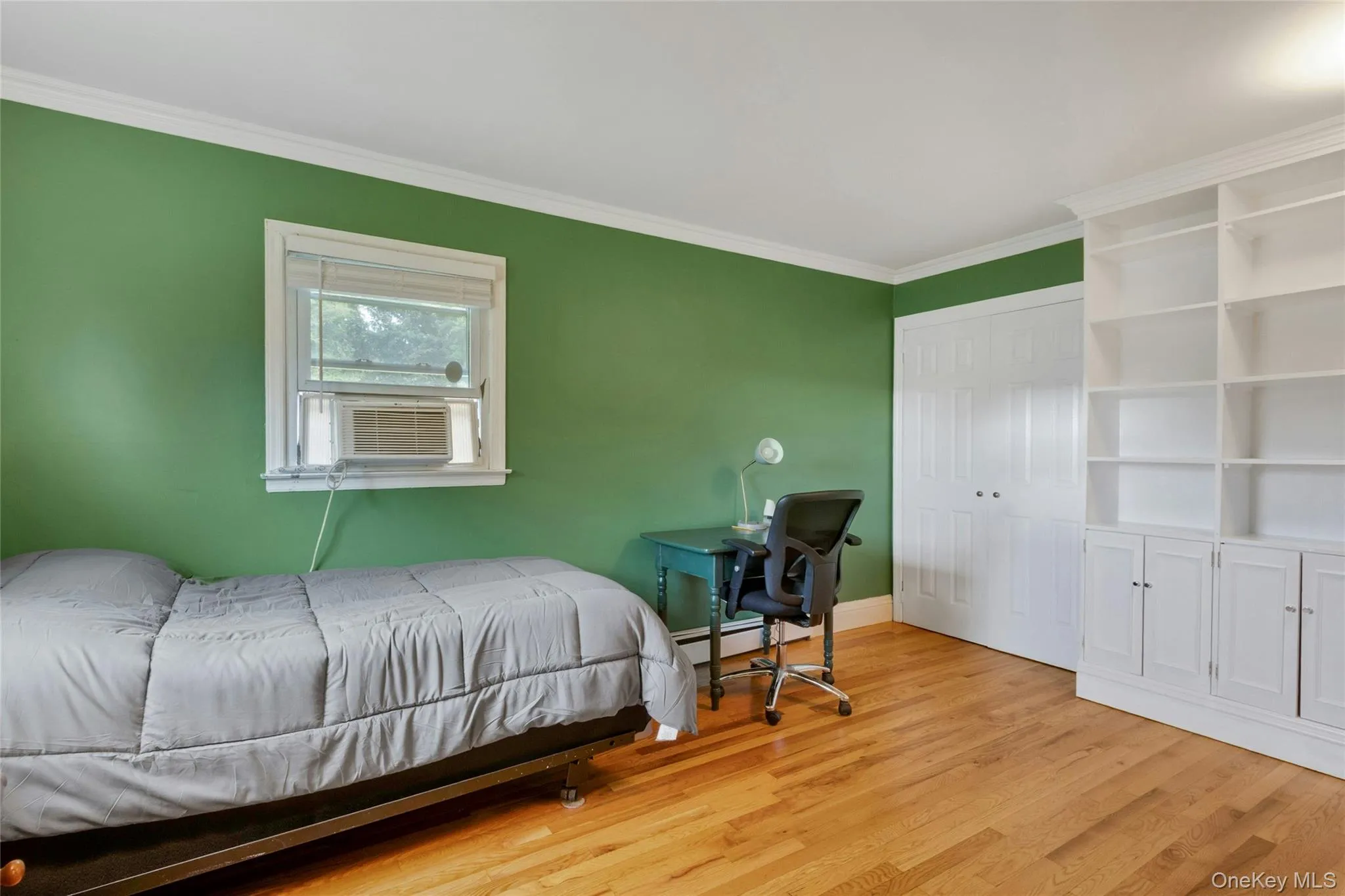Hardwood flooring, crown molding, built-in shelving, built-in cabinetry, and a window with an air conditioning unit Hardwood flooring, crown molding, built-in shelving, built-in cabinetry, and a window with an air conditioning unit