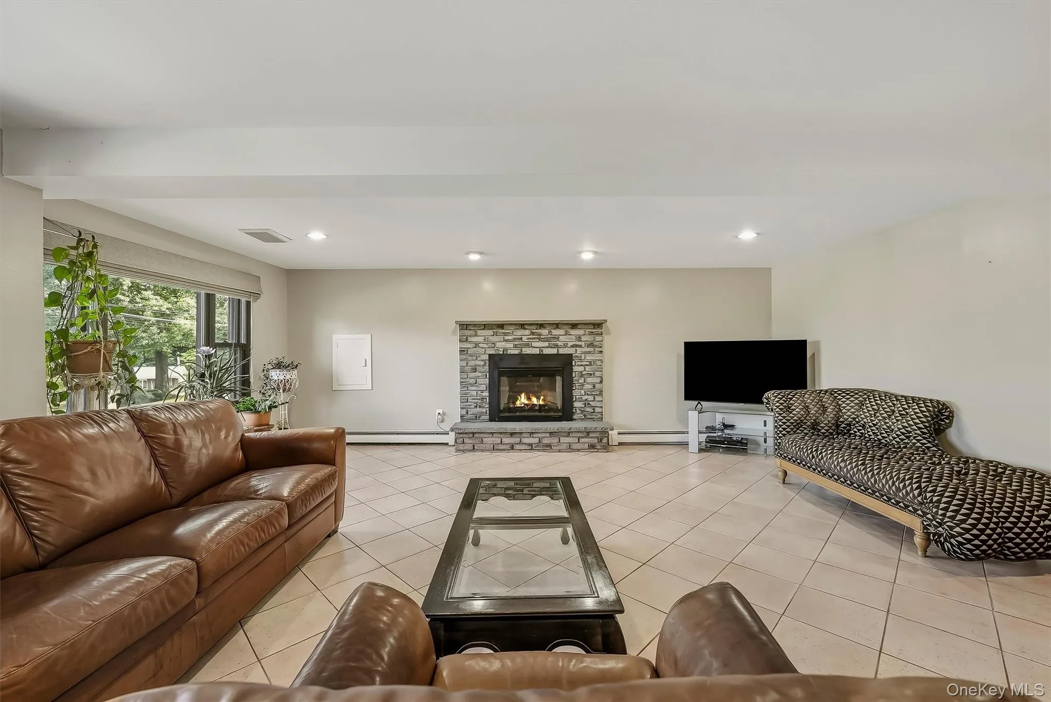 Stone-faced fireplace with hearth, tile flooring, recessed lighting, and large windows Stone-faced fireplace with hearth, tile flooring, recessed lighting, and large windows