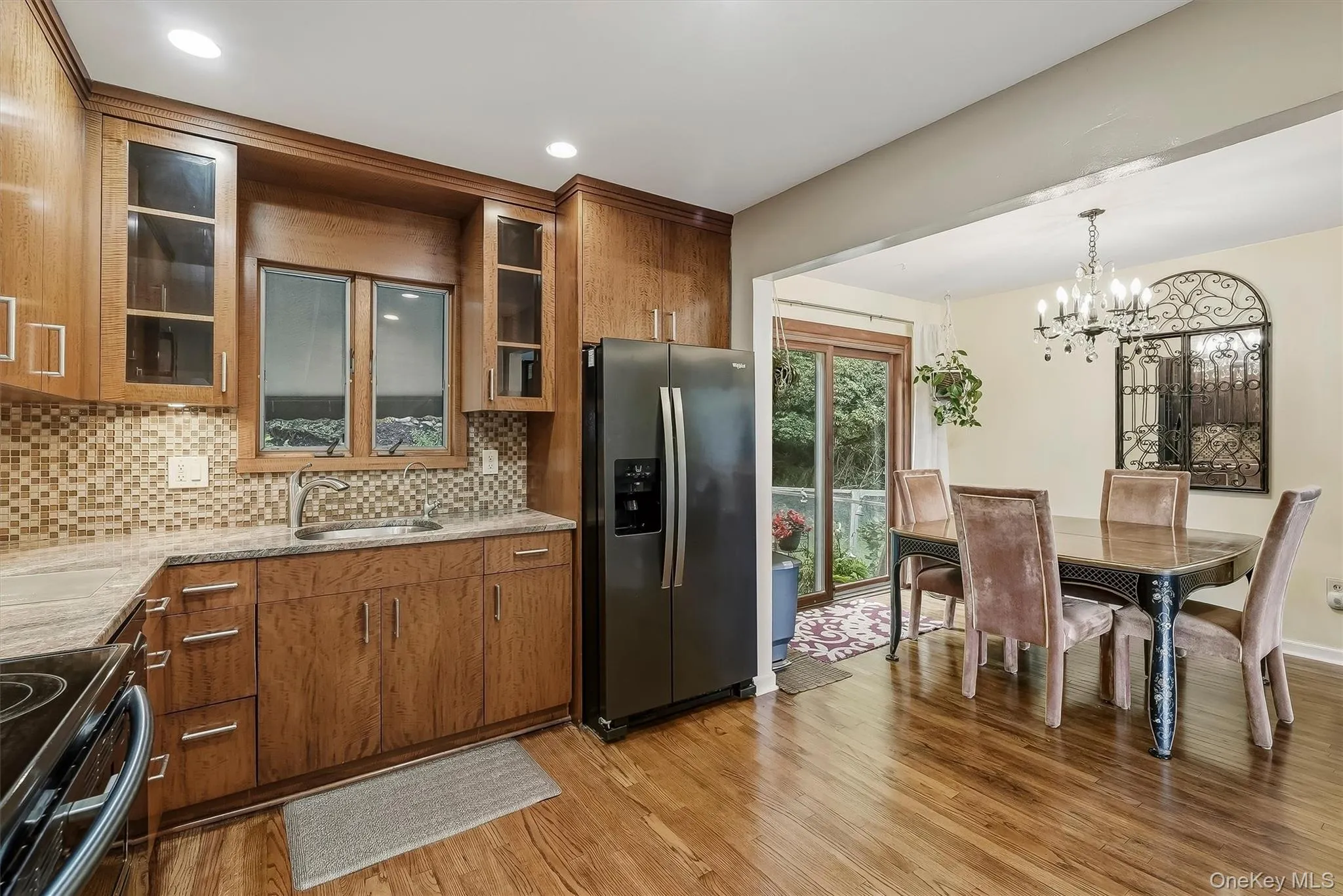 Kitchen featuring wood cabinetry and flooring with access to dining area and backyard. Kitchen featuring wood cabinetry and flooring with access to dining area and backyard.