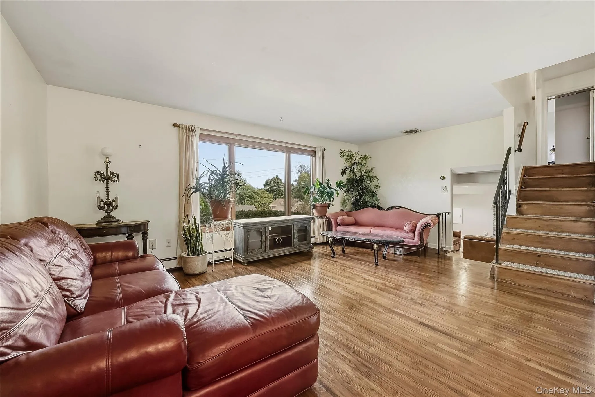 Second level living room featuring wood flooring, and a large window with a view. Steps lead up to bedroom level or down to recreation room. Second level living room featuring wood flooring, and a large window with a view. Steps lead up to bedroom level or down to recreation room.