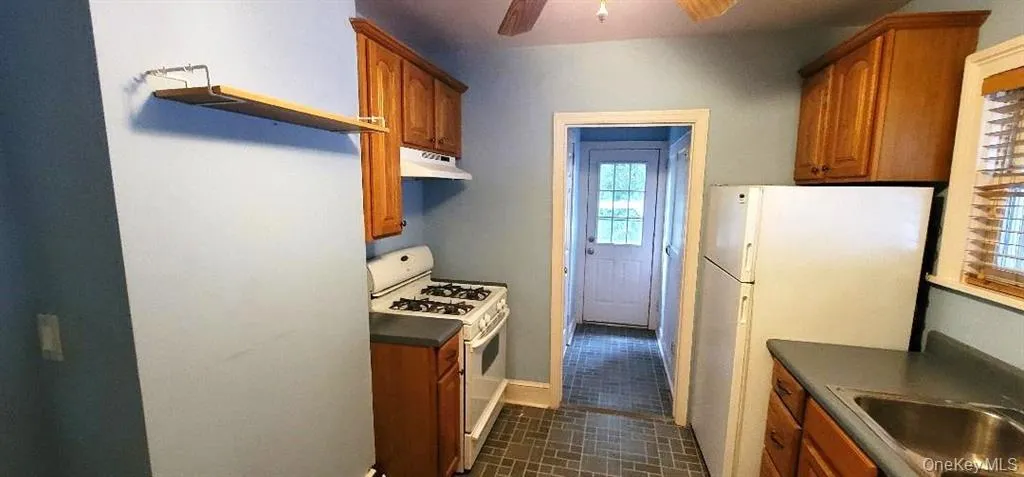 Kitchen featuring sink, ceiling fan, white appliances, and vynal patterned floors Kitchen featuring sink, ceiling fan, white appliances, and vynal patterned floors