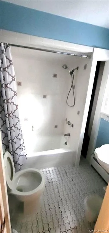 Bathroom featuring tile patterned flooring, shower / bath combo with shower curtain, and toilet Bathroom featuring tile patterned flooring, shower / bath combo with shower curtain, and toilet
