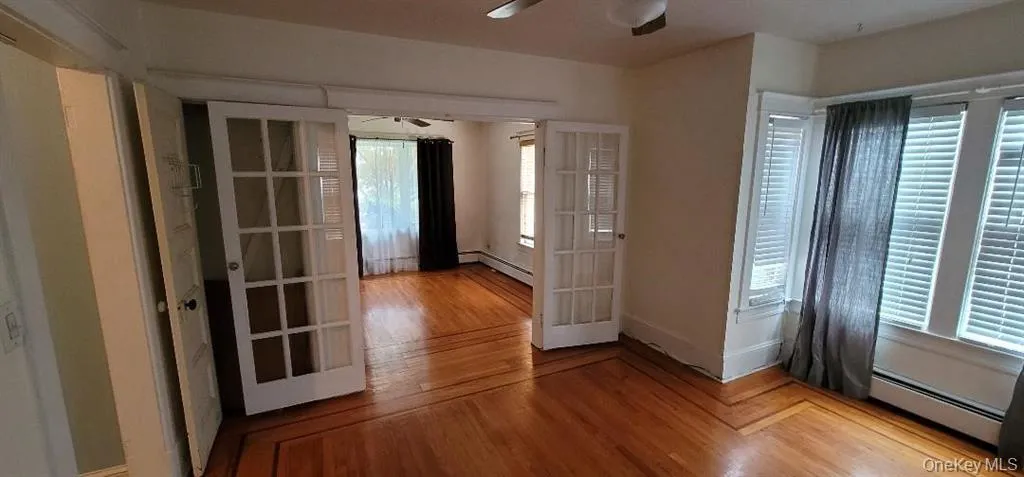 glass French Doors between Living and bedroom with light hardwood / wood-style floors, a baseboard heating unit, and ceiling fan glass French Doors between Living and bedroom with light hardwood / wood-style floors, a baseboard heating unit, and ceiling fan