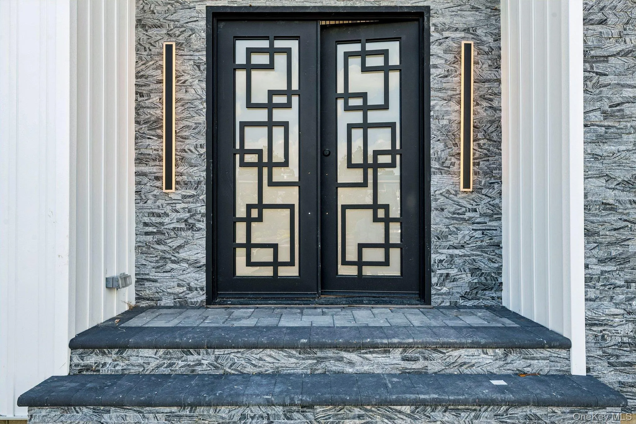 Double-door entry featuring geometric glass inserts and black framing Double-door entry featuring geometric glass inserts and black framing