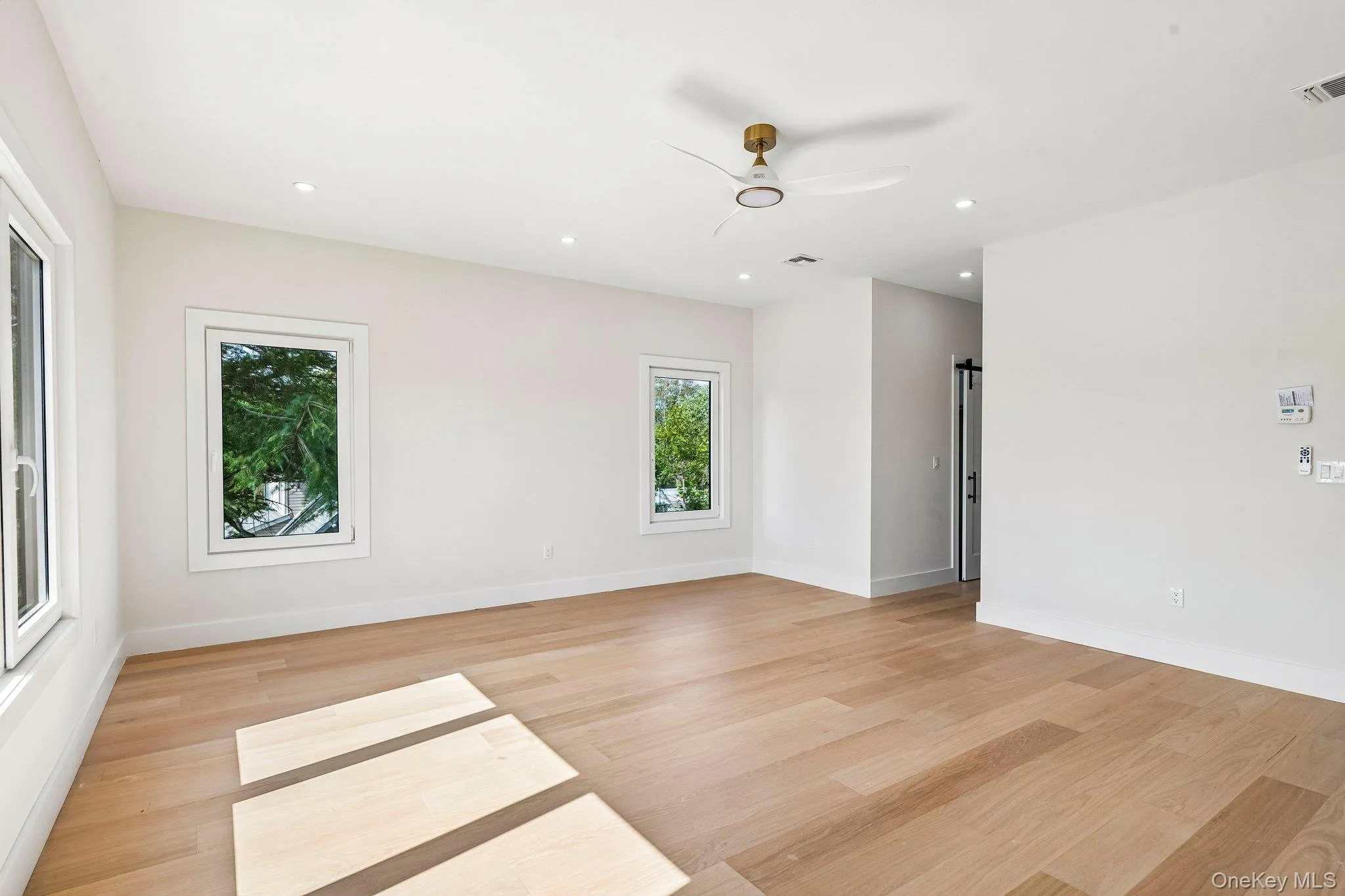 Light wood-finish flooring, recessed lighting, white walls, multiple windows, and a modern ceiling fan Light wood-finish flooring, recessed lighting, white walls, multiple windows, and a modern ceiling fan