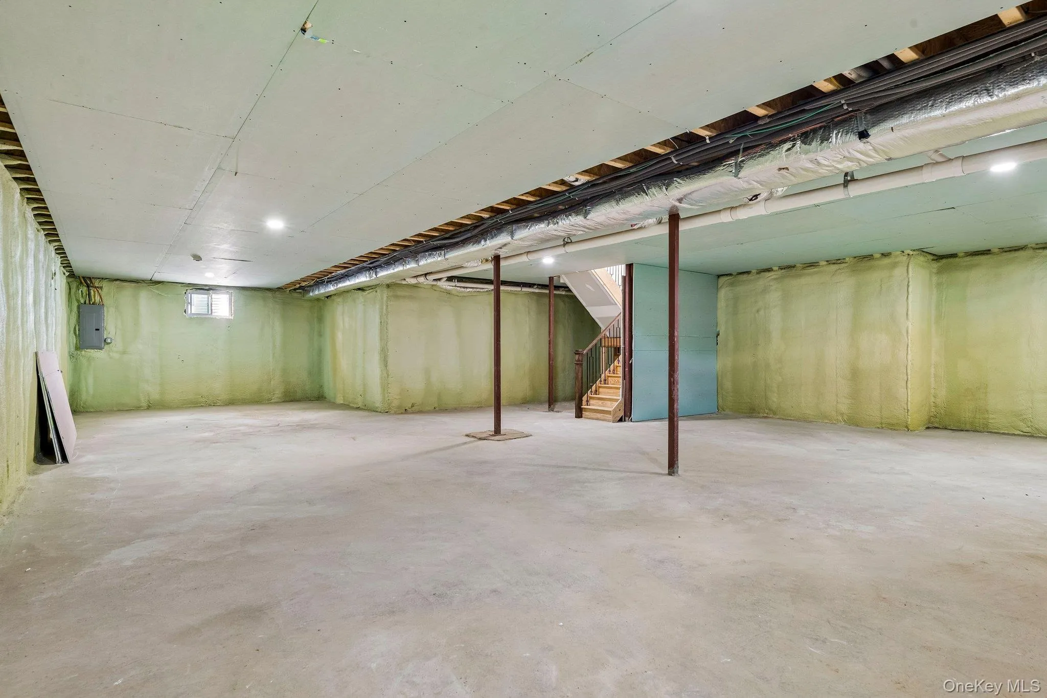 Spacious unfinished lower level with concrete flooring, recessed lighting, exposed ceiling joists, and a window Spacious unfinished lower level with concrete flooring, recessed lighting, exposed ceiling joists, and a window