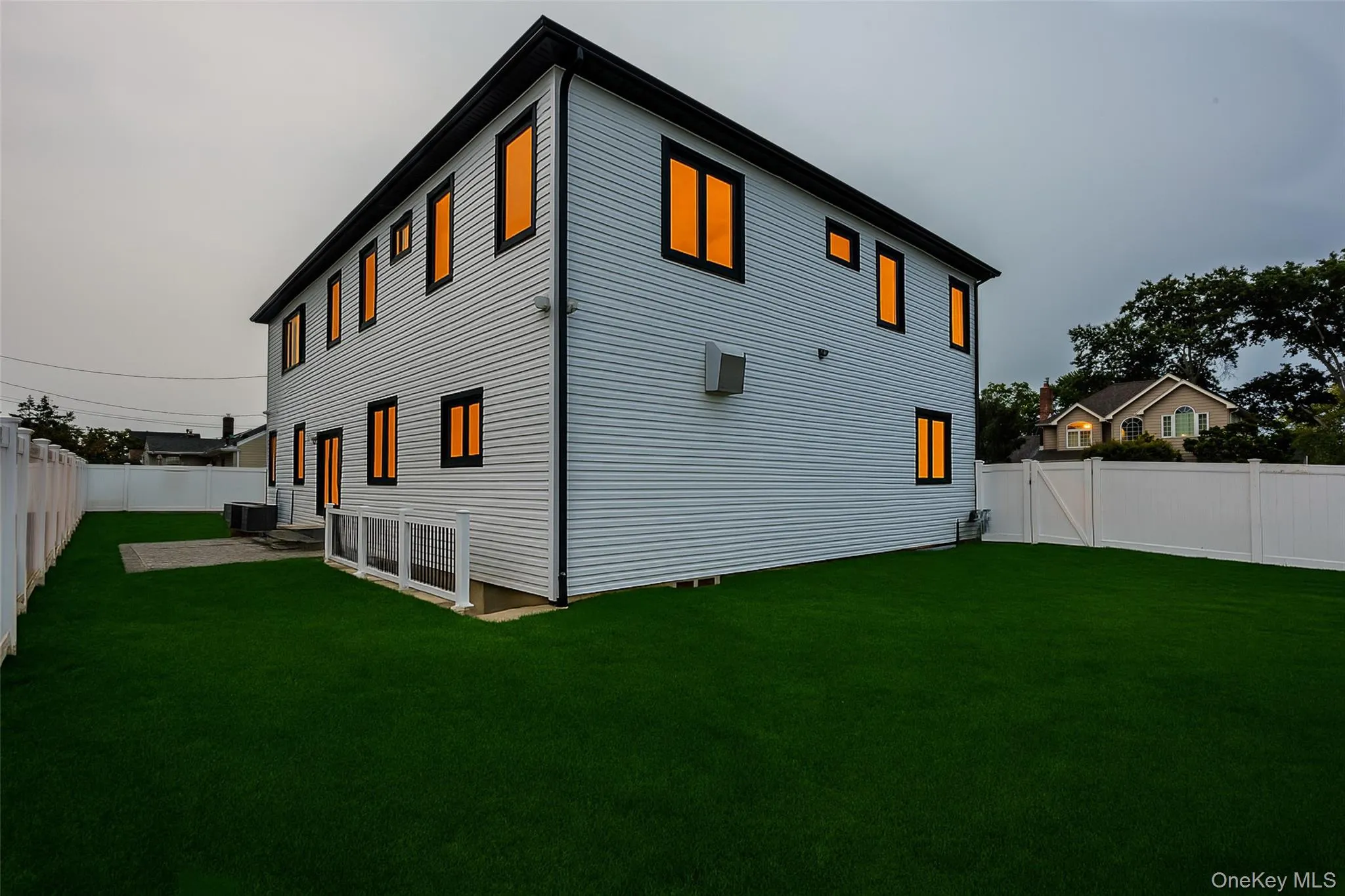 Fenced yard with artificial turf, a paver patio, and a two-story exterior featuring white siding and black trim windows Fenced yard with artificial turf, a paver patio, and a two-story exterior featuring white siding and black trim windows