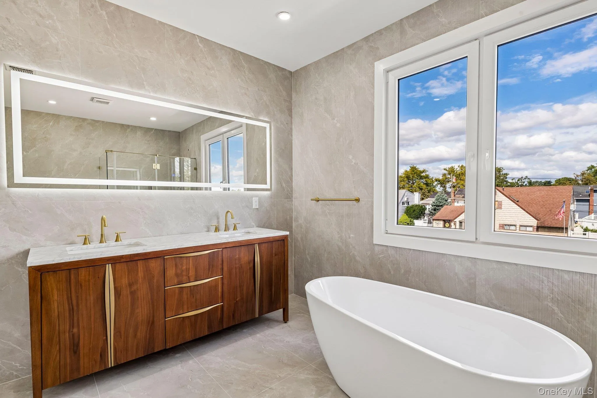 Freestanding soaking tub, dual-pane windows, wood-finish double vanity with stone countertop, and an illuminated mirror Freestanding soaking tub, dual-pane windows, wood-finish double vanity with stone countertop, and an illuminated mirror