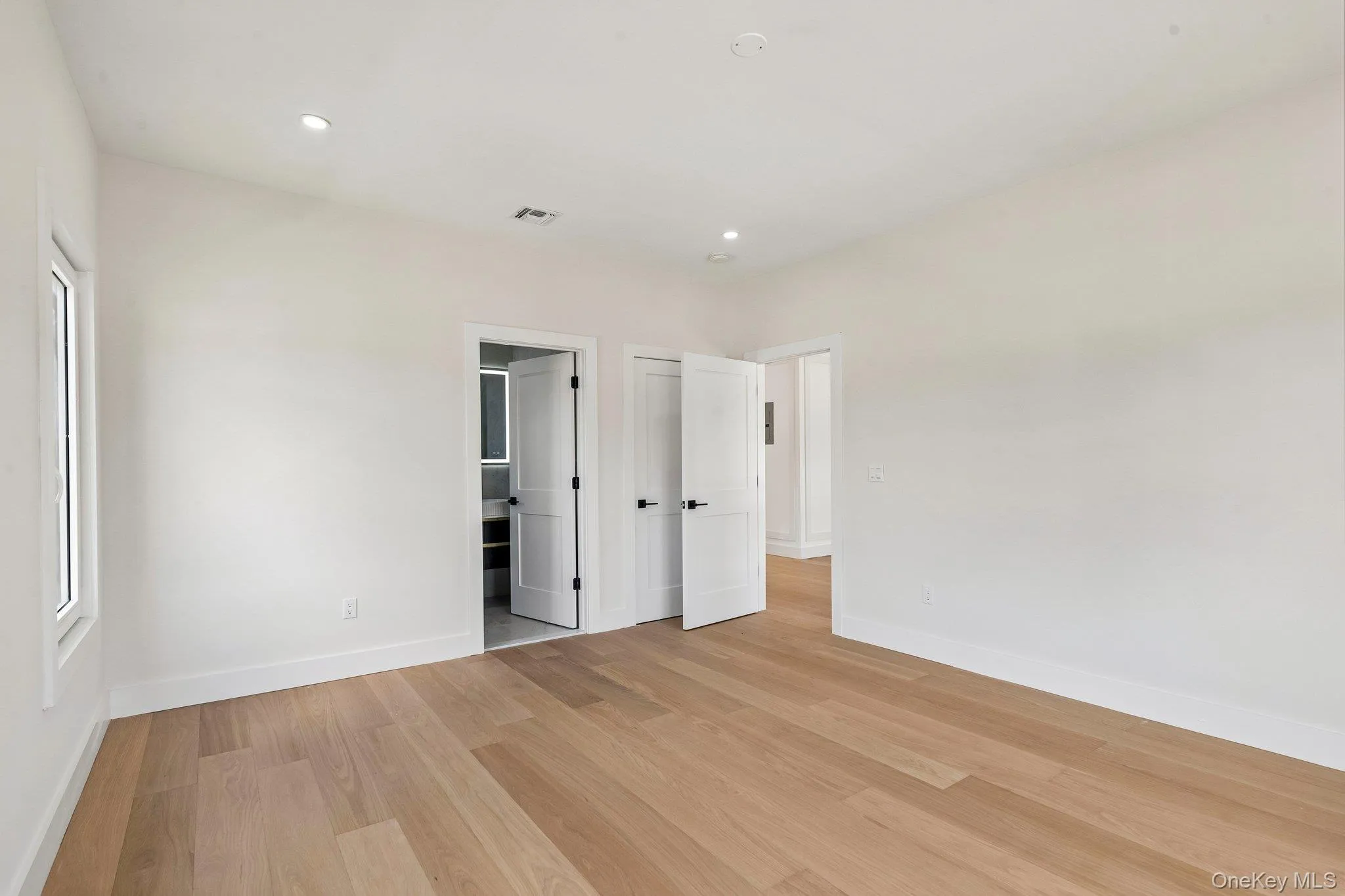 Recessed lighting, wood-finish flooring, white walls, white trim, and white doors with matte black hardware Recessed lighting, wood-finish flooring, white walls, white trim, and white doors with matte black hardware