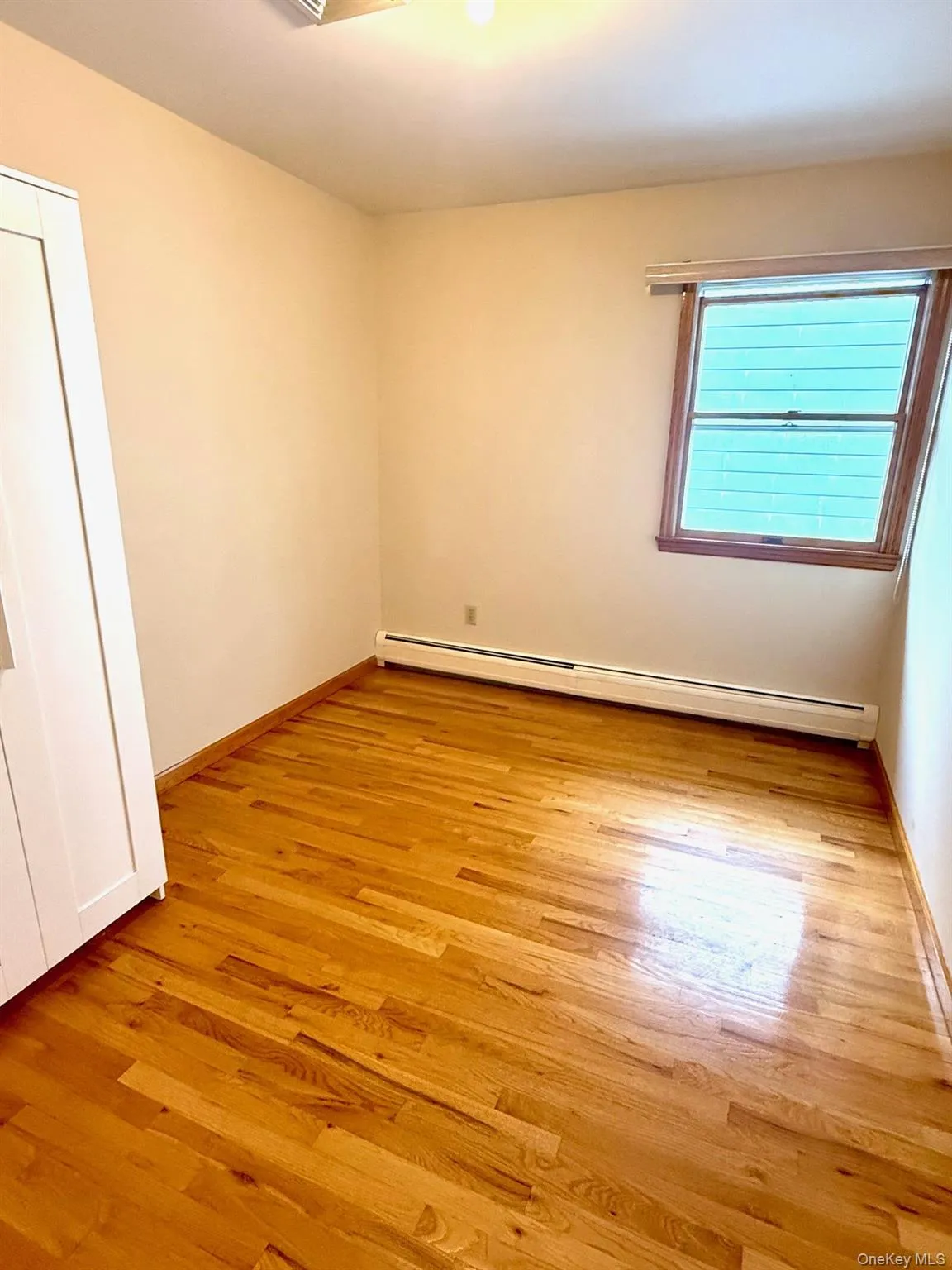 Spare room with a baseboard heating unit and light wood-type flooring Spare room with a baseboard heating unit and light wood-type flooring