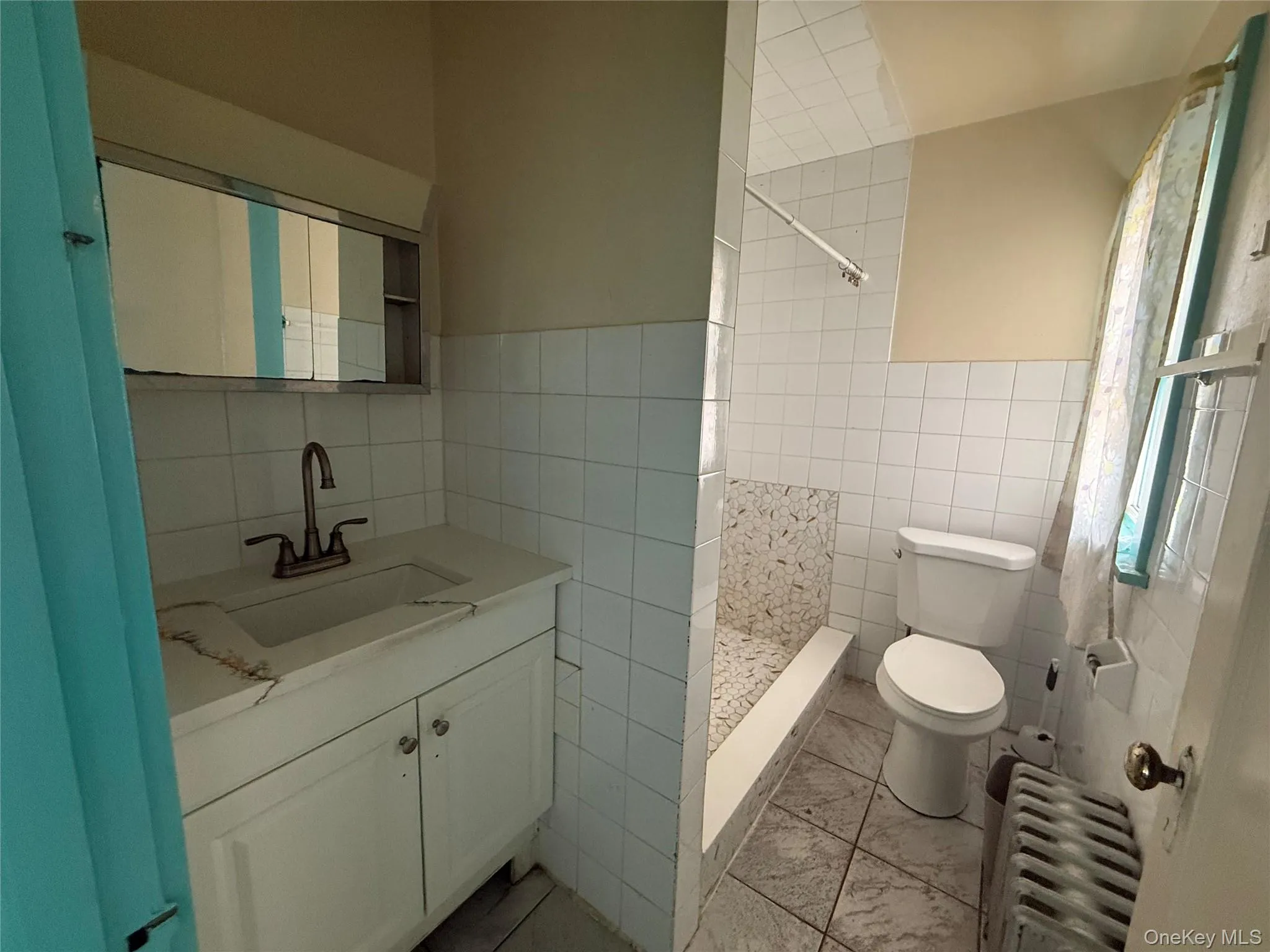 Bathroom featuring a stall shower, tile walls, vanity, and radiator Bathroom featuring a stall shower, tile walls, vanity, and radiator