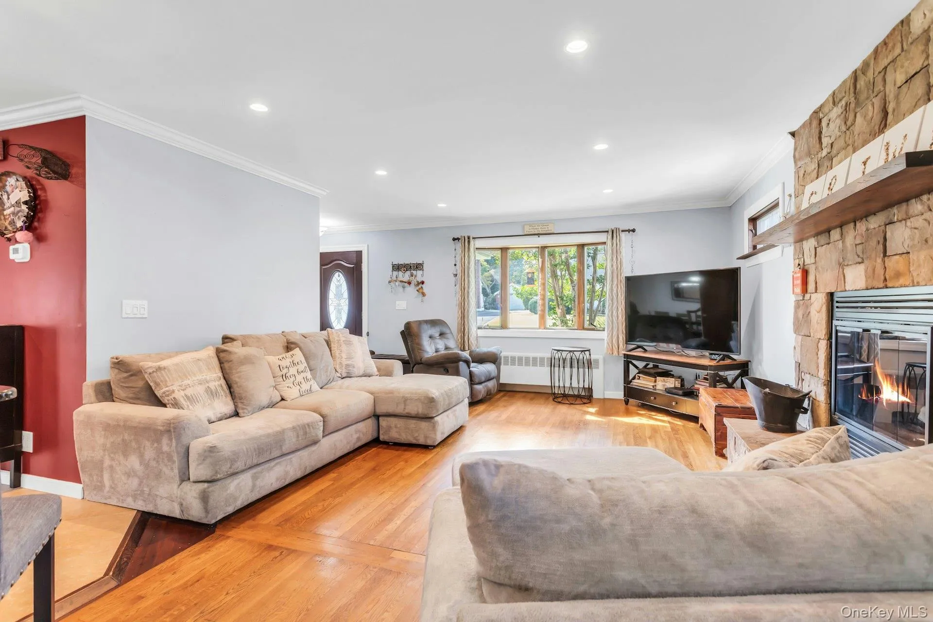Recessed lighting, wood-finish flooring, and a stone-clad fireplace with a wood mantel Recessed lighting, wood-finish flooring, and a stone-clad fireplace with a wood mantel