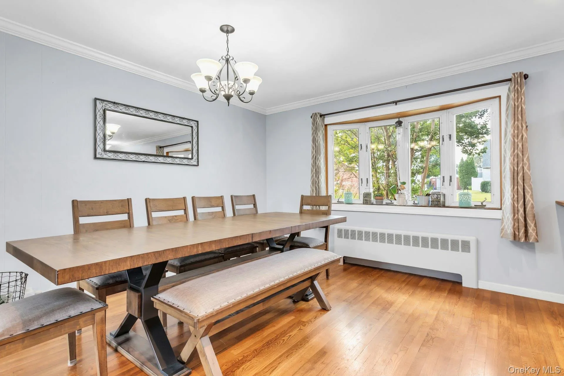 Hardwood flooring throughout, featuring a bay window with a wide sill, crown molding, and an overhead chandelier Hardwood flooring throughout, featuring a bay window with a wide sill, crown molding, and an overhead chandelier