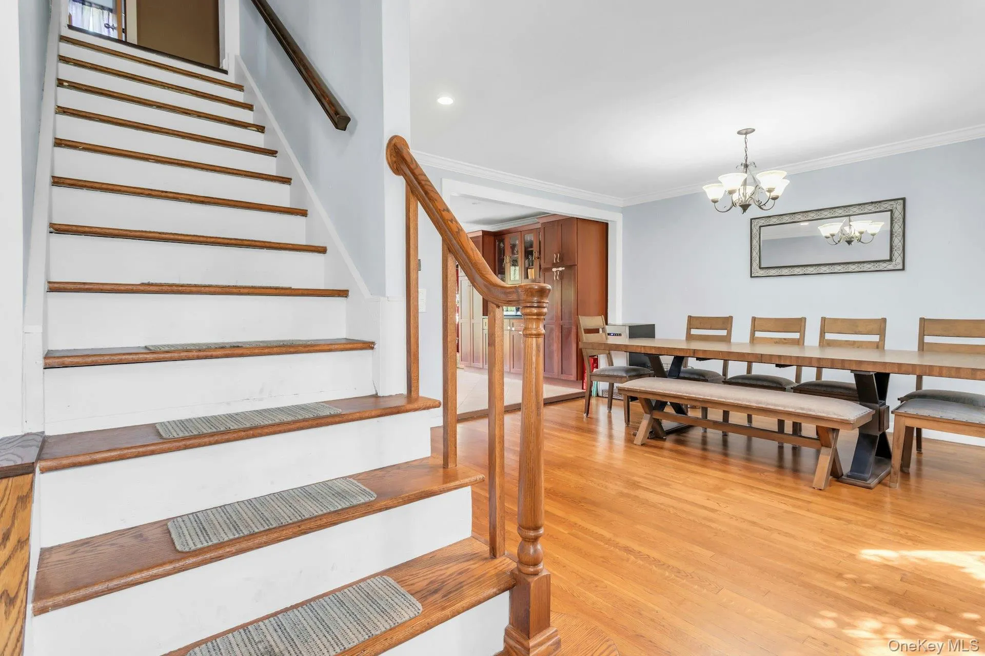 Hardwood flooring throughout, crown molding, chandelier lighting, recessed lighting, and a wood staircase with a matching banister Hardwood flooring throughout, crown molding, chandelier lighting, recessed lighting, and a wood staircase with a matching banister
