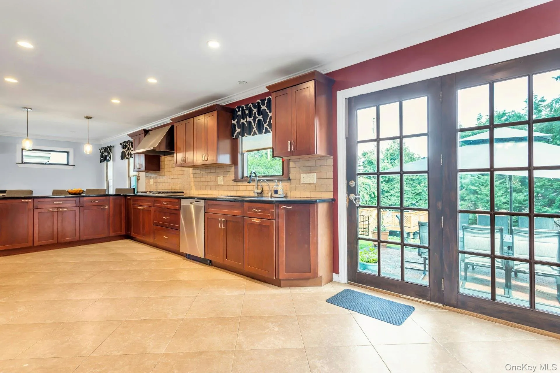 U-shaped kitchen featuring wood cabinetry, stainless steel appliances, dark countertops, a subway tile backsplash, and recessed lighting U-shaped kitchen featuring wood cabinetry, stainless steel appliances, dark countertops, a subway tile backsplash, and recessed lighting