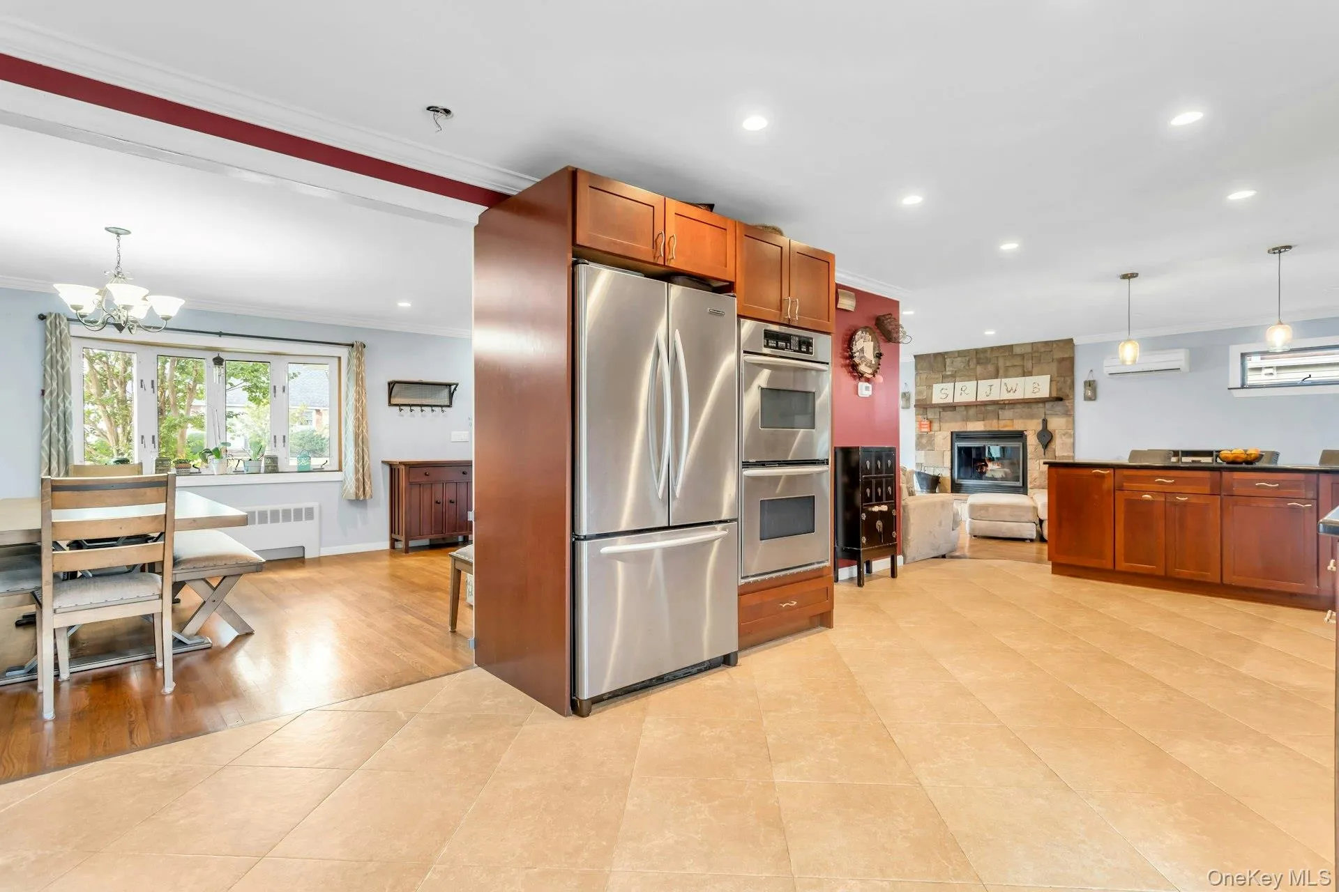 Stainless steel double oven, integrated stainless steel refrigerator, kitchen island with dark countertop, stone-clad fireplace, and recessed lighting Stainless steel double oven, integrated stainless steel refrigerator, kitchen island with dark countertop, stone-clad fireplace, and recessed lighting