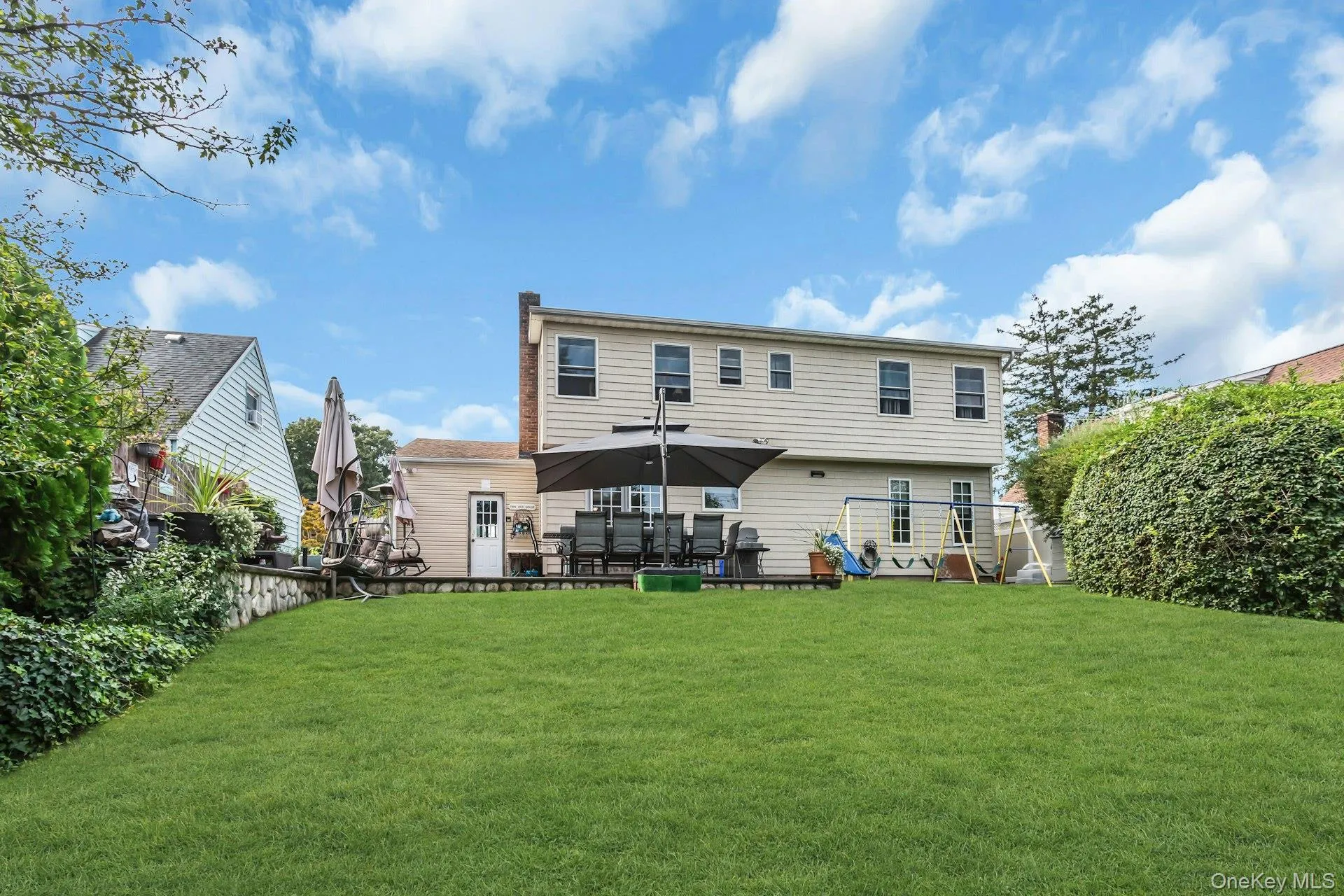 Expansive green lawn with a retaining wall, complemented by mature privacy landscaping Expansive green lawn with a retaining wall, complemented by mature privacy landscaping