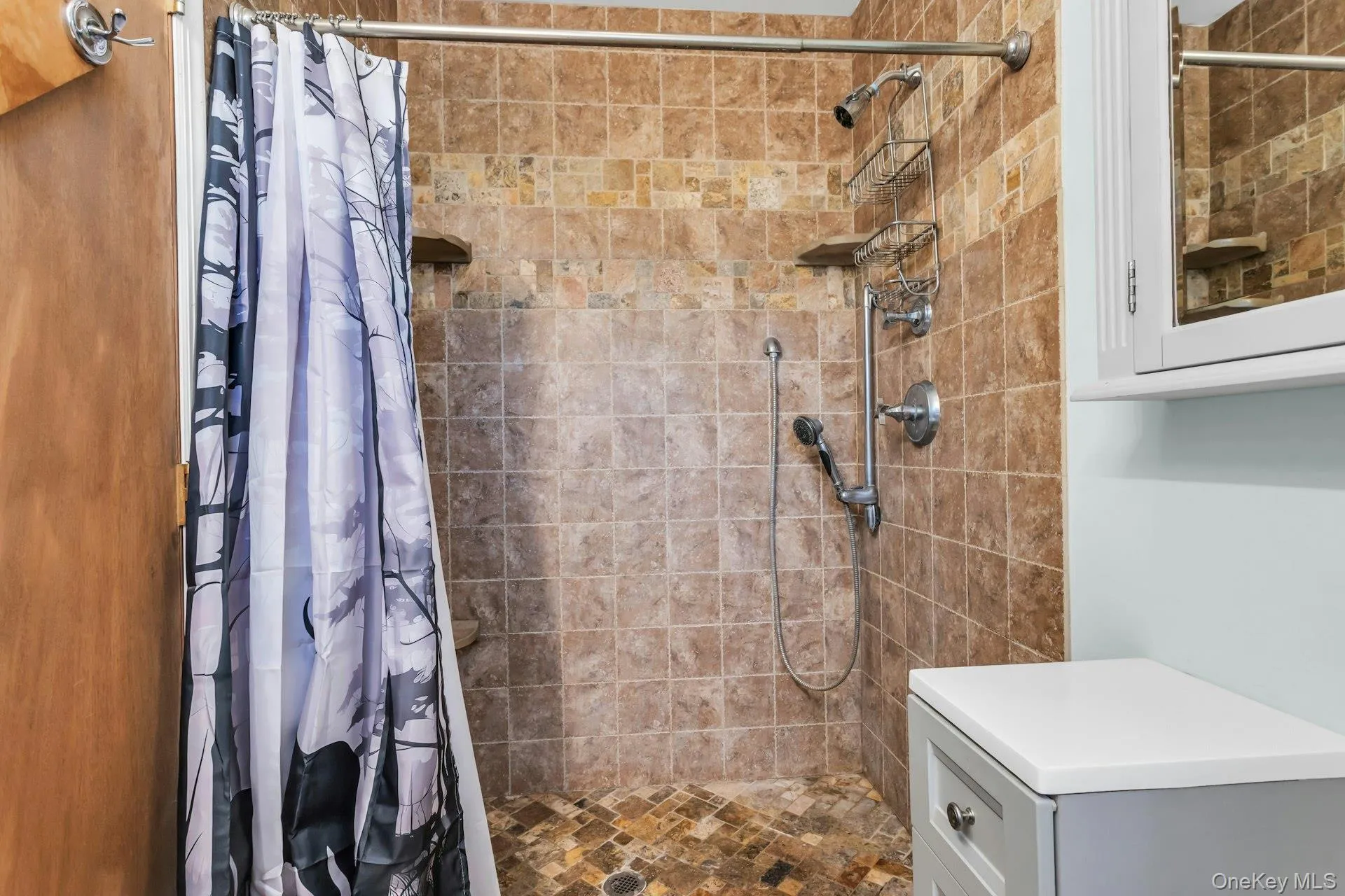 Tiled shower enclosure featuring a handheld showerhead and built-in shelving Tiled shower enclosure featuring a handheld showerhead and built-in shelving