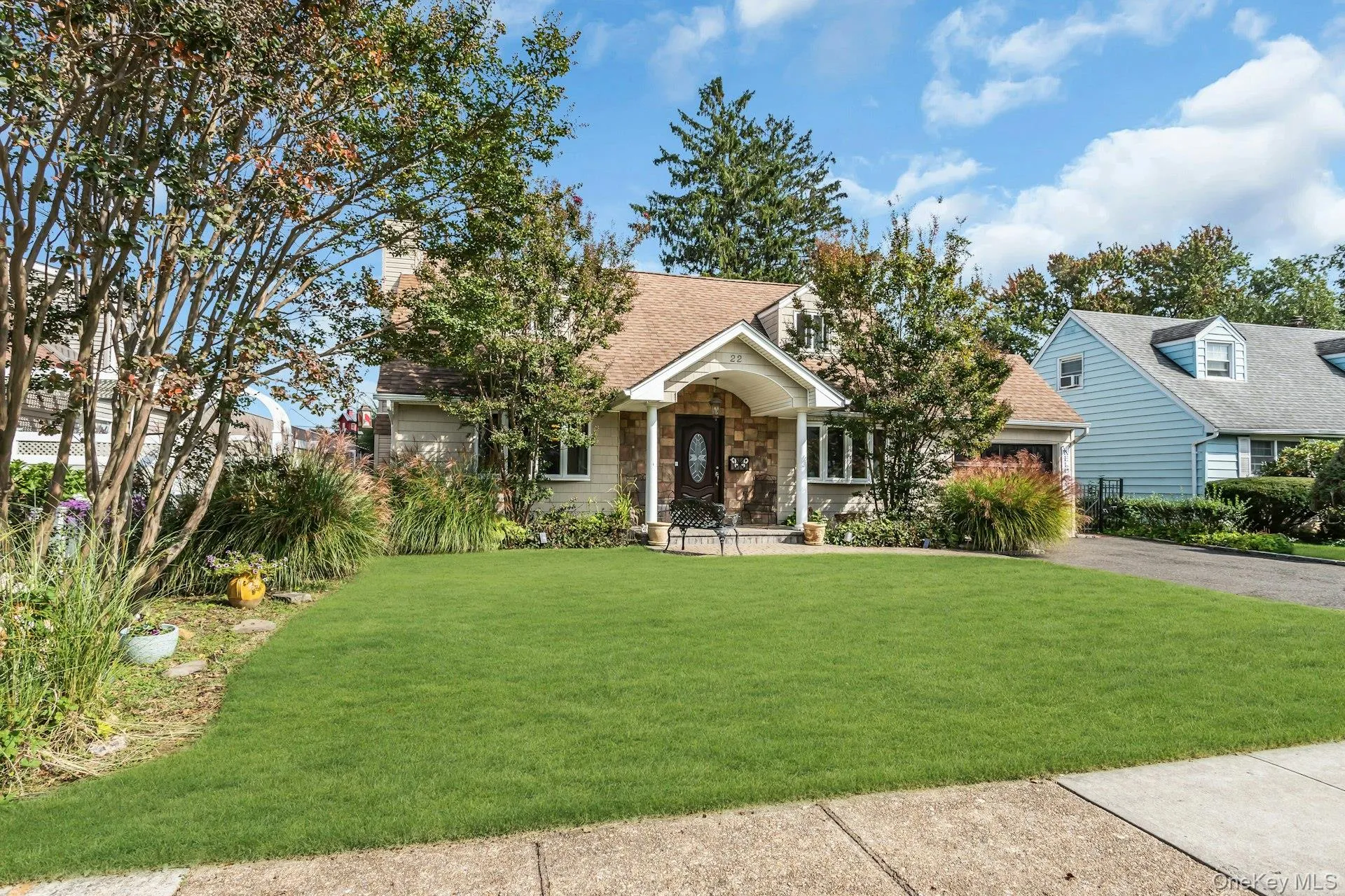 Manicured front lawn, stone facade, covered entry, and attached garage Manicured front lawn, stone facade, covered entry, and attached garage