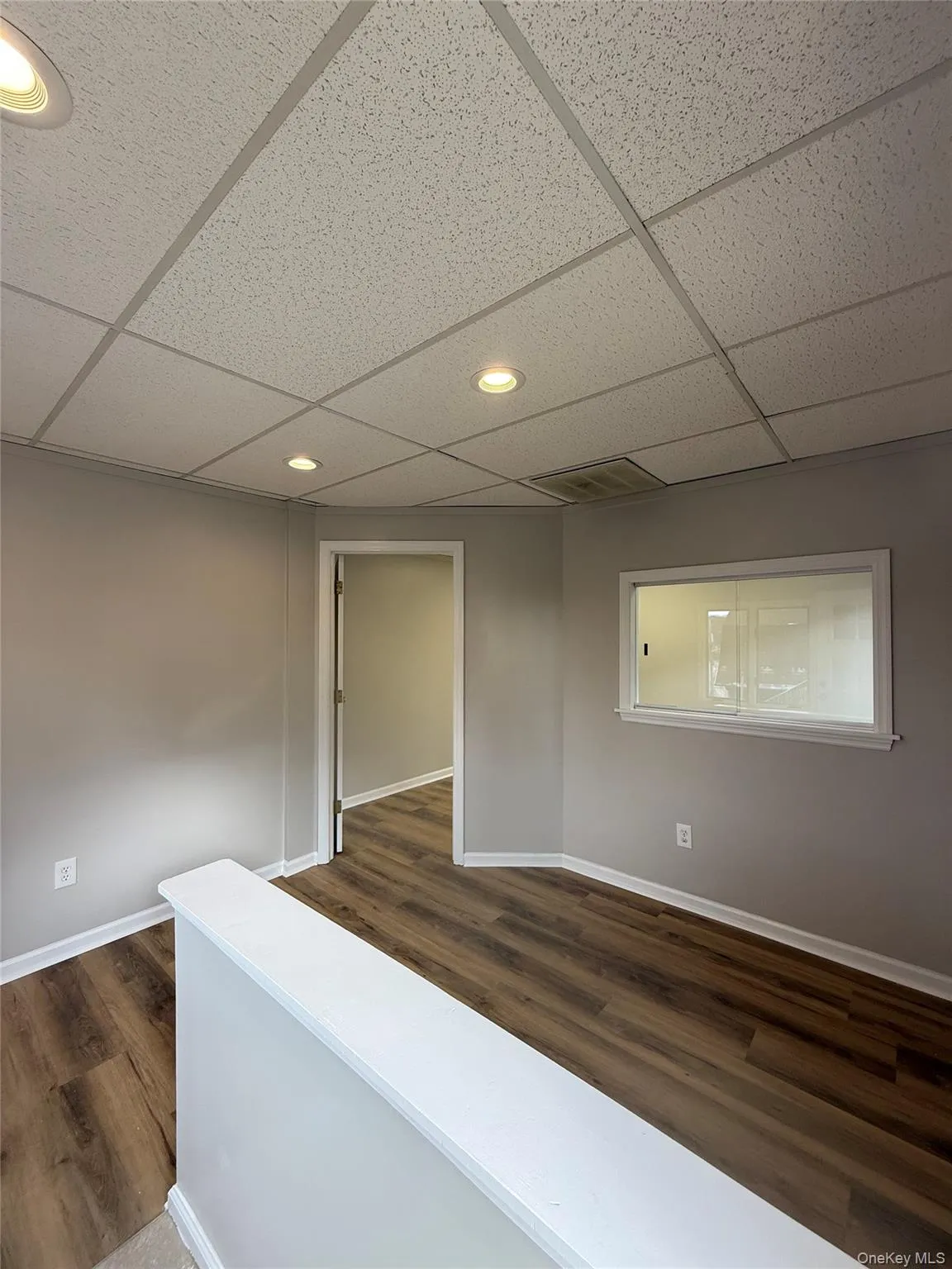 Hallway featuring a drop ceiling, recessed lighting, and dark wood-style floors Hallway featuring a drop ceiling, recessed lighting, and dark wood-style floors