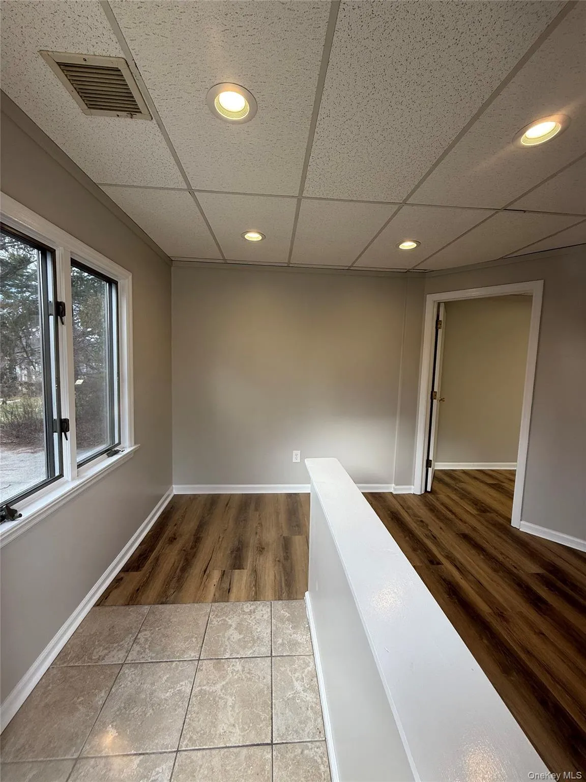 Corridor with dark tile patterned floors, a drop ceiling, and recessed lighting Corridor with dark tile patterned floors, a drop ceiling, and recessed lighting