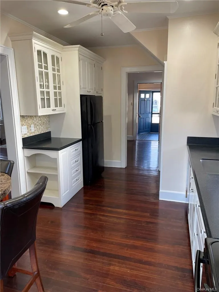 Kitchen featuring white cabinets, black appliances, dark hardwood floors and fan. Kitchen featuring white cabinets, black appliances, dark hardwood floors and fan.