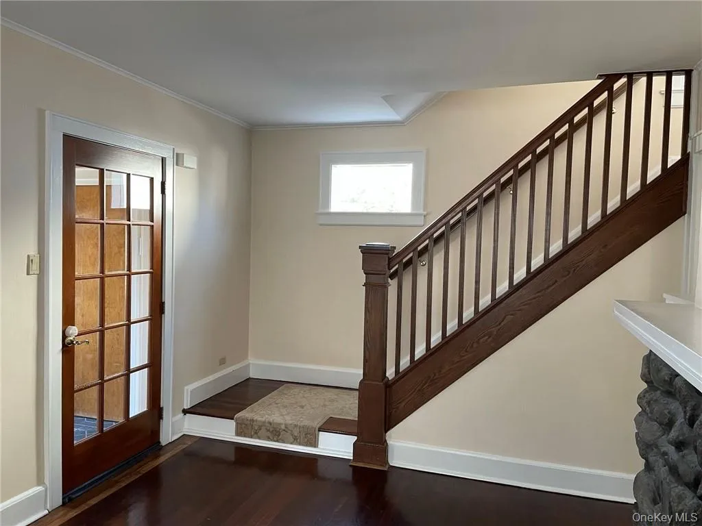 Living room featuring dark hardwood floors, molding and access to entry/mud room Living room featuring dark hardwood floors, molding and access to entry/mud room