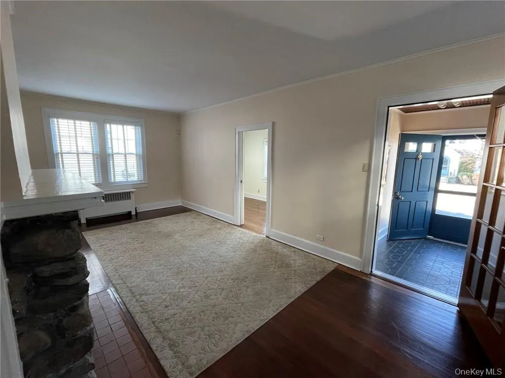 Living room featuring dark hardwood floors, molding and access to office and entry/mud room Living room featuring dark hardwood floors, molding and access to office and entry/mud room