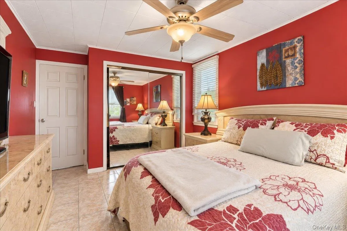 Textured tile flooring, ceiling fan, white paneled door, mirrored closet doors, and window with blinds Textured tile flooring, ceiling fan, white paneled door, mirrored closet doors, and window with blinds