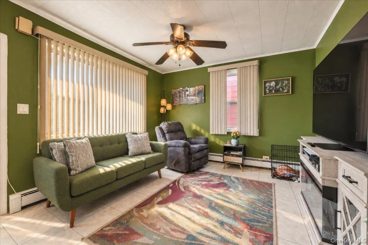 Living area with tile flooring, a ceiling fan with integrated lighting, and multiple windows with vertical blinds Living area with tile flooring, a ceiling fan with integrated lighting, and multiple windows with vertical blinds