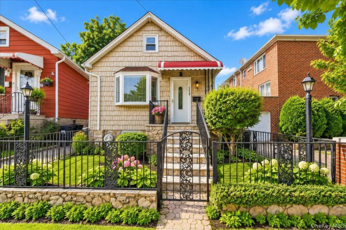 Gabled shingle-sided exterior with a bay window, red awning, and wrought iron fencing Gabled shingle-sided exterior with a bay window, red awning, and wrought iron fencing