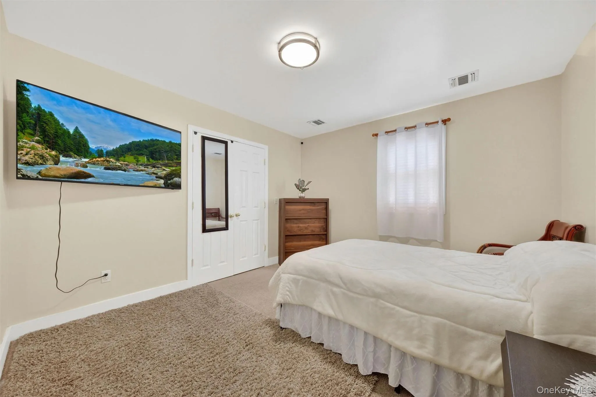 Neutral wall paint, carpet flooring, a window with blinds, and a ceiling-mounted light fixture Neutral wall paint, carpet flooring, a window with blinds, and a ceiling-mounted light fixture