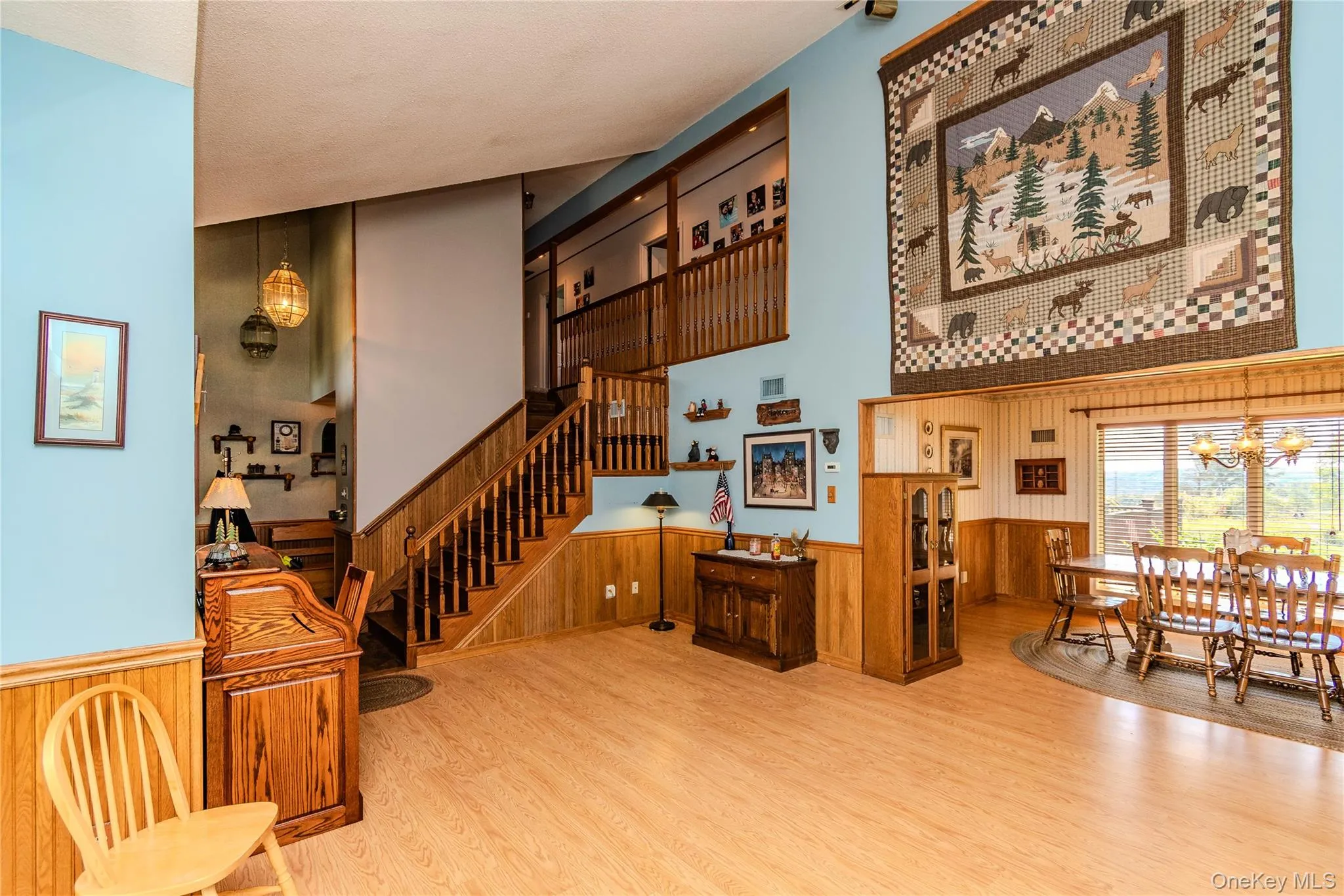 Vaulted ceiling, wood-finish flooring, wood paneling, open-concept design, and a multi-level staircase with wood railing Vaulted ceiling, wood-finish flooring, wood paneling, open-concept design, and a multi-level staircase with wood railing