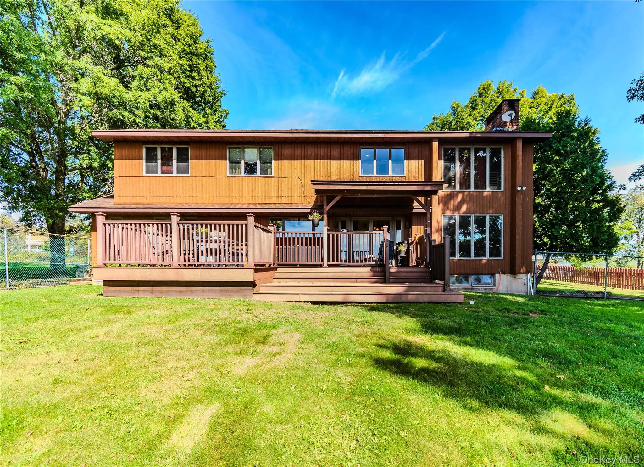Expansive backyard with a manicured lawn, a multi-level wood deck, and a wood-sided exterior Expansive backyard with a manicured lawn, a multi-level wood deck, and a wood-sided exterior