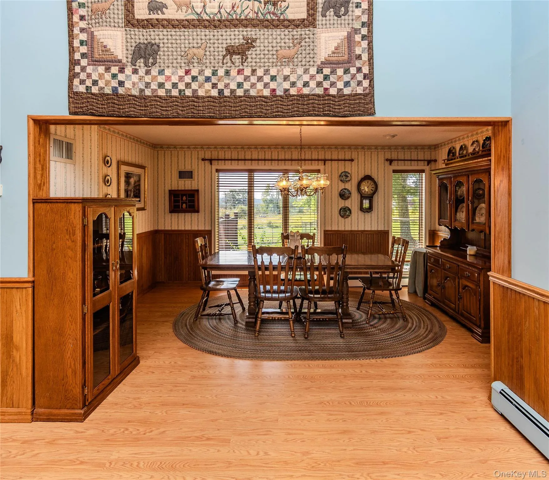 Wood-finish flooring throughout, with a dining area featuring wood wall paneling and a chandelier Wood-finish flooring throughout, with a dining area featuring wood wall paneling and a chandelier