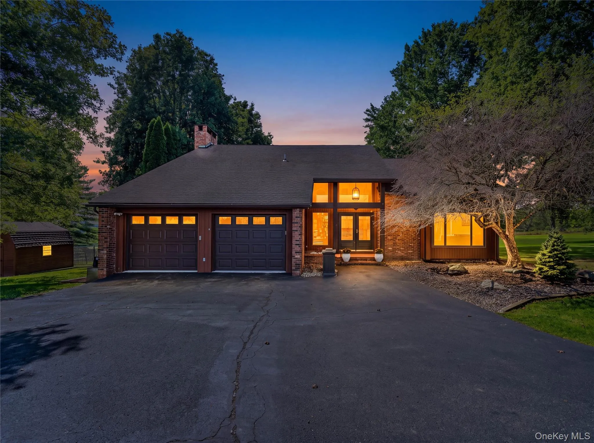 Brick exterior with a dark shingled roof, featuring a prominent chimney Brick exterior with a dark shingled roof, featuring a prominent chimney