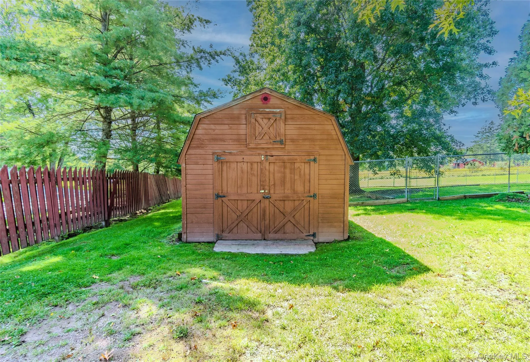 Barn-style shed with double doors, wood siding, and an overhead window Barn-style shed with double doors, wood siding, and an overhead window