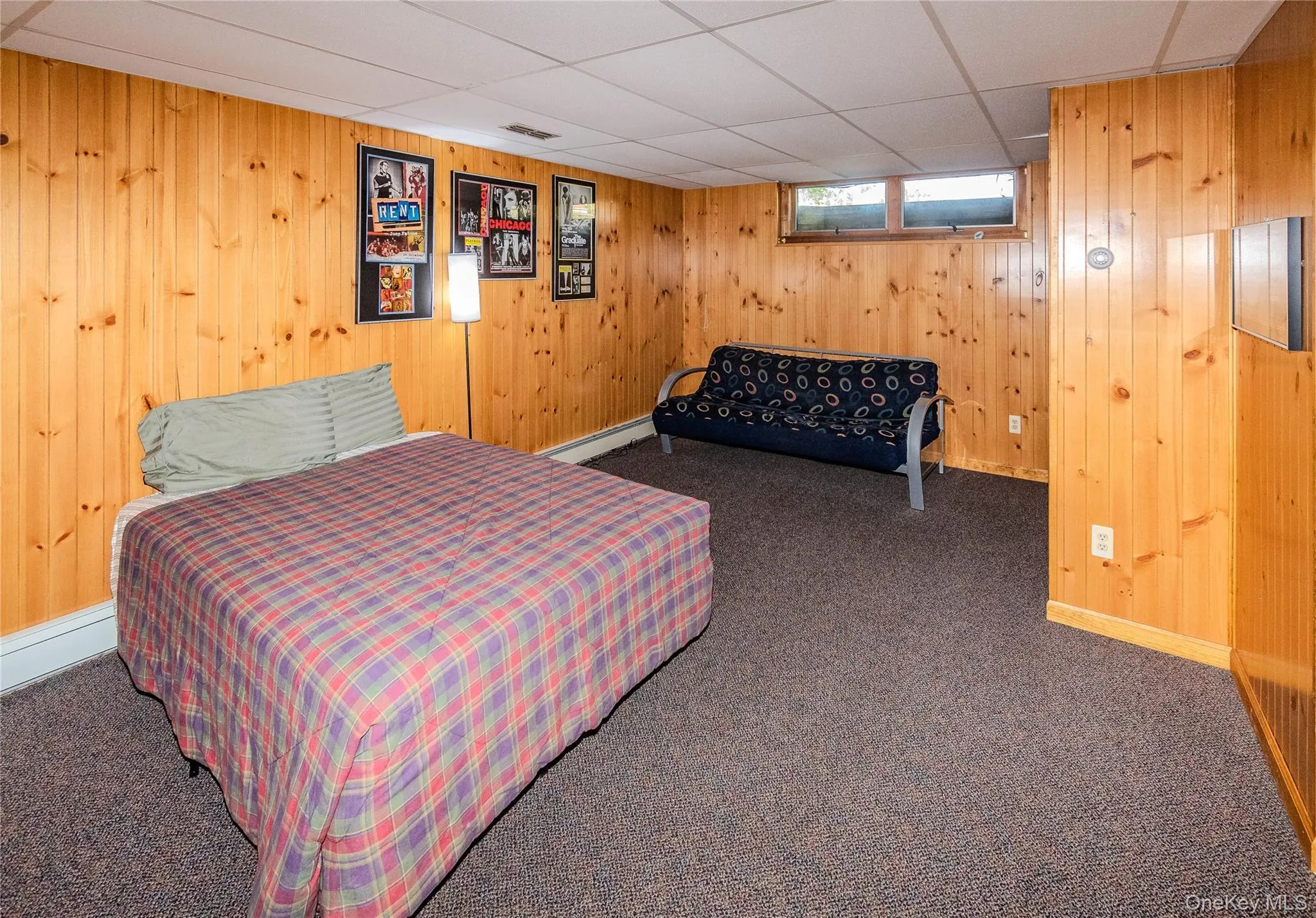 Wood-paneled walls with carpet flooring and a drop ceiling Wood-paneled walls with carpet flooring and a drop ceiling