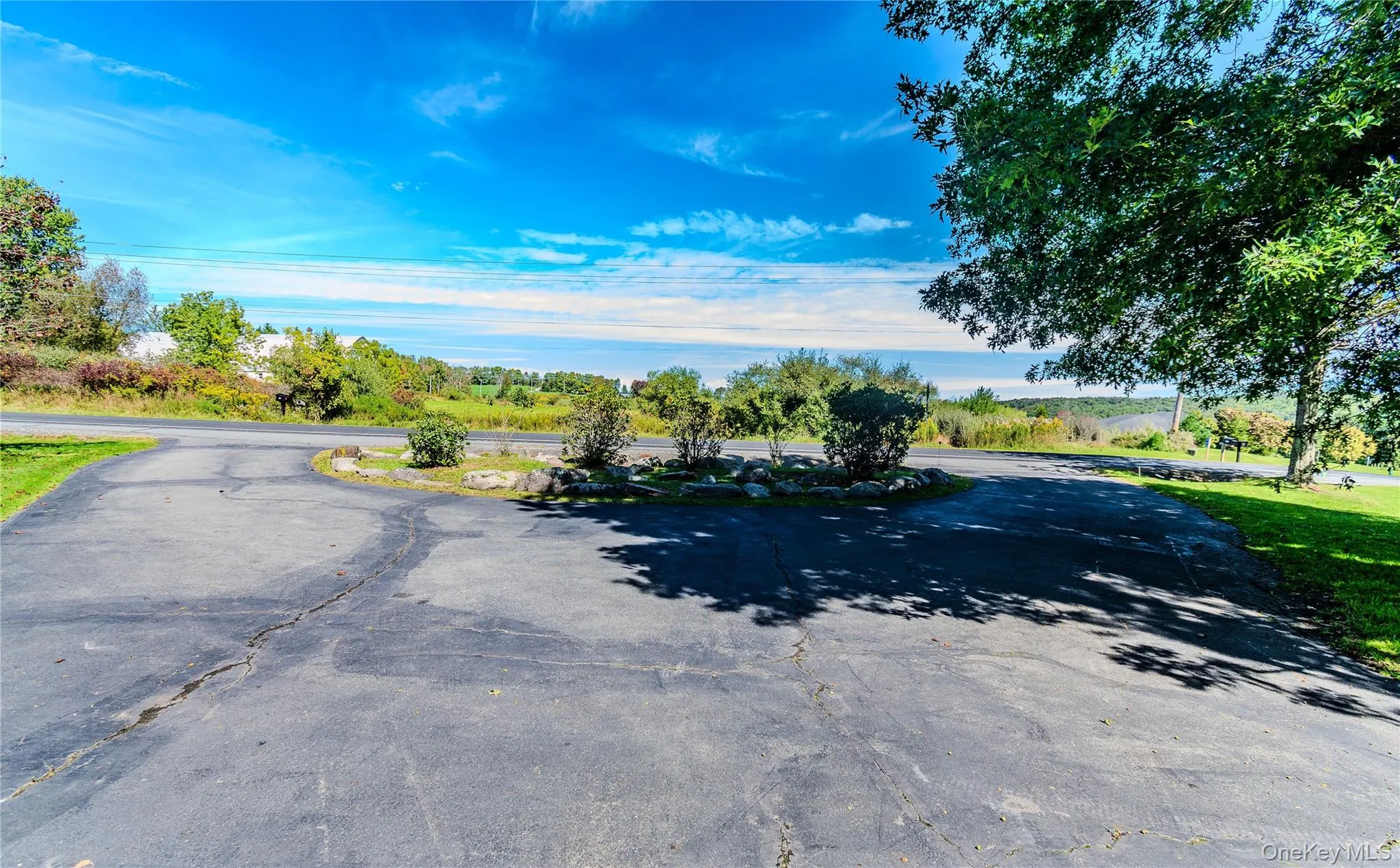 Asphalt driveway with a circular turnaround, surrounded by mature trees and landscaping Asphalt driveway with a circular turnaround, surrounded by mature trees and landscaping