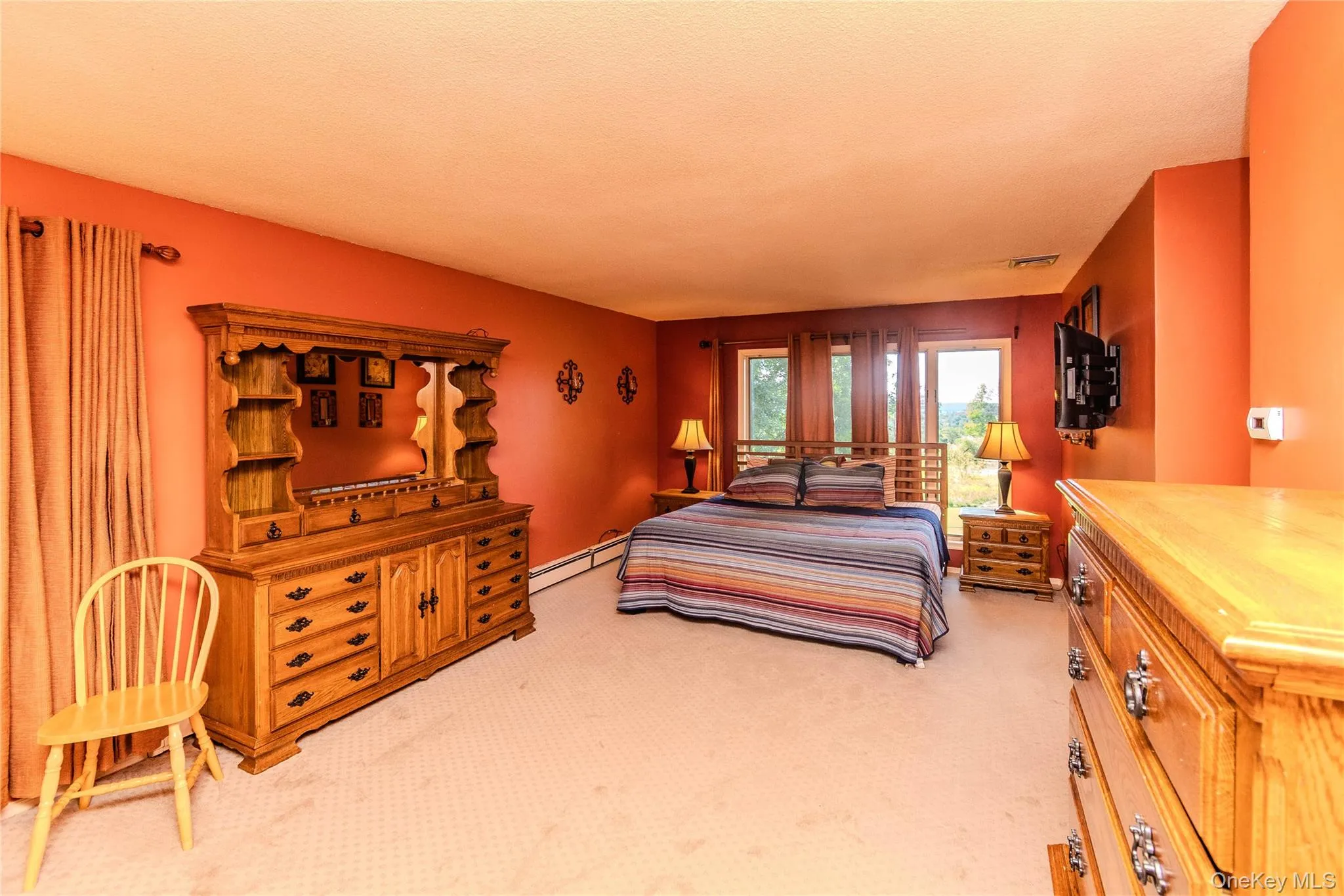 Expansive room with carpeted flooring, multiple windows, and a wall-mounted television bracket Expansive room with carpeted flooring, multiple windows, and a wall-mounted television bracket