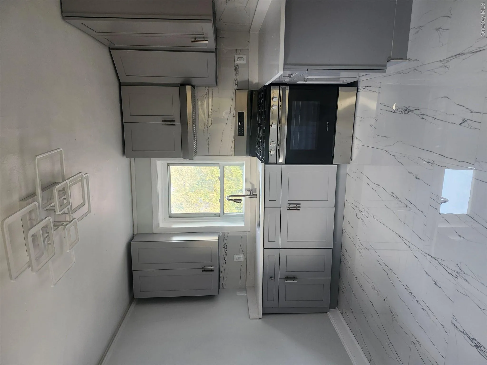 Modern kitchen featuring grey cabinetry, stainless steel oven with range hood, white countertops, and full backsplash Modern kitchen featuring grey cabinetry, stainless steel oven with range hood, white countertops, and full backsplash