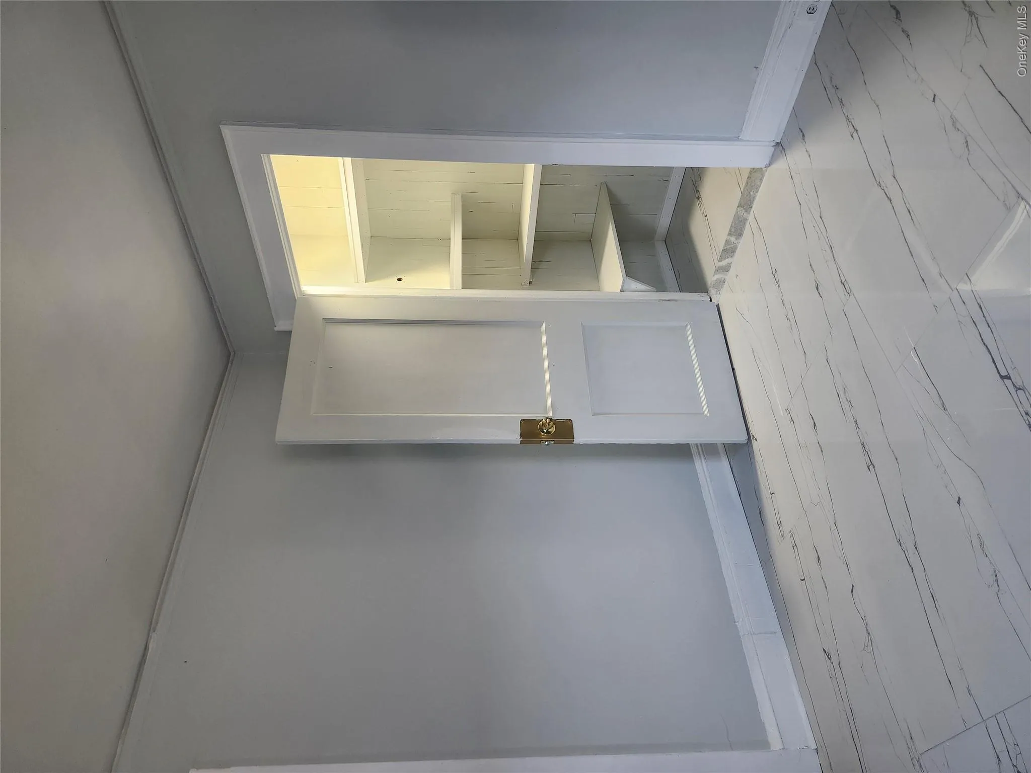 White-painted walls with crown molding, a built-in closet with shelving, and large format tile flooring White-painted walls with crown molding, a built-in closet with shelving, and large format tile flooring