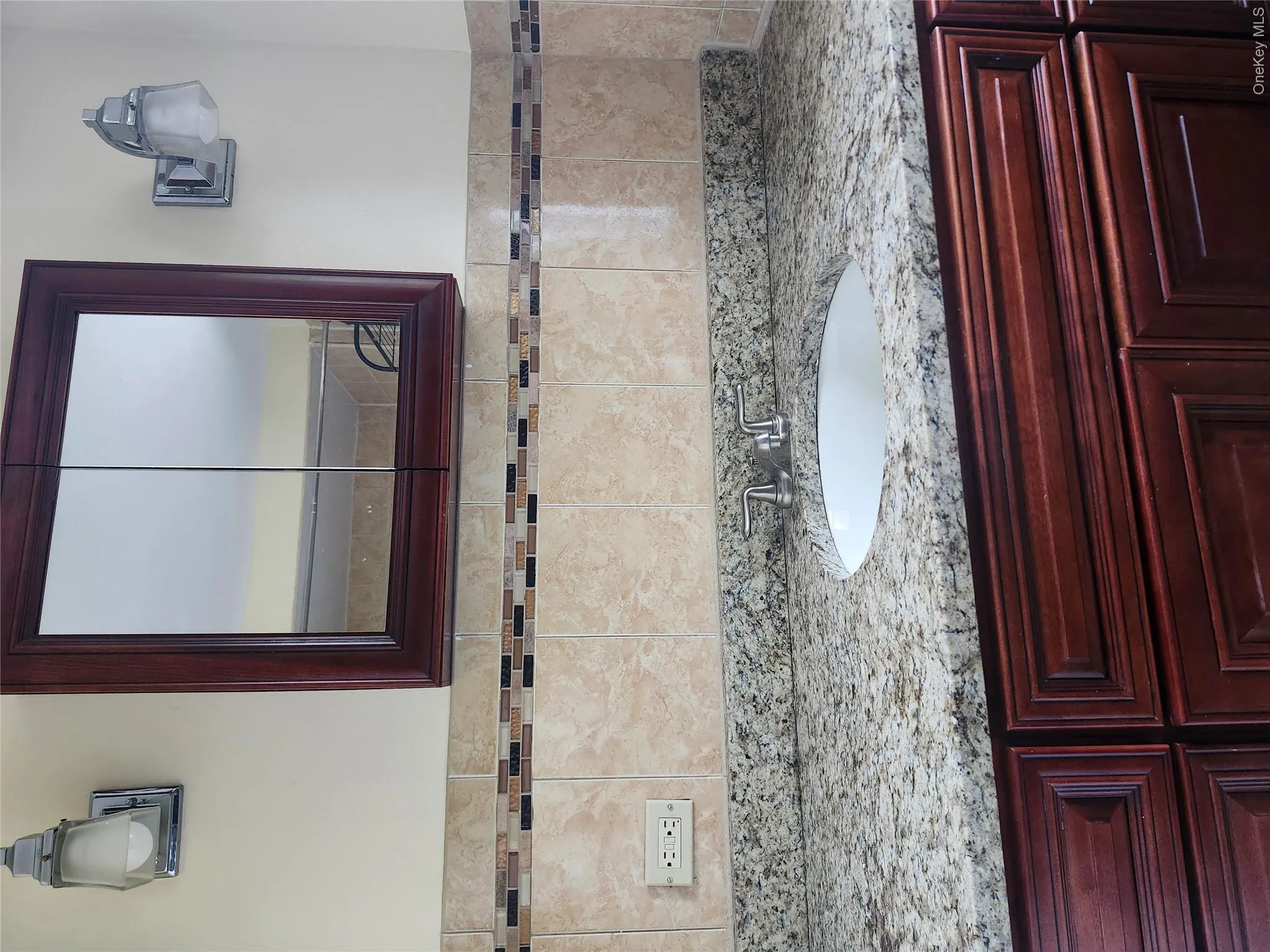 Elegant bathroom vanity featuring rich wood cabinetry, speckled stone countertop, and vessel sink with chrome faucet Elegant bathroom vanity featuring rich wood cabinetry, speckled stone countertop, and vessel sink with chrome faucet