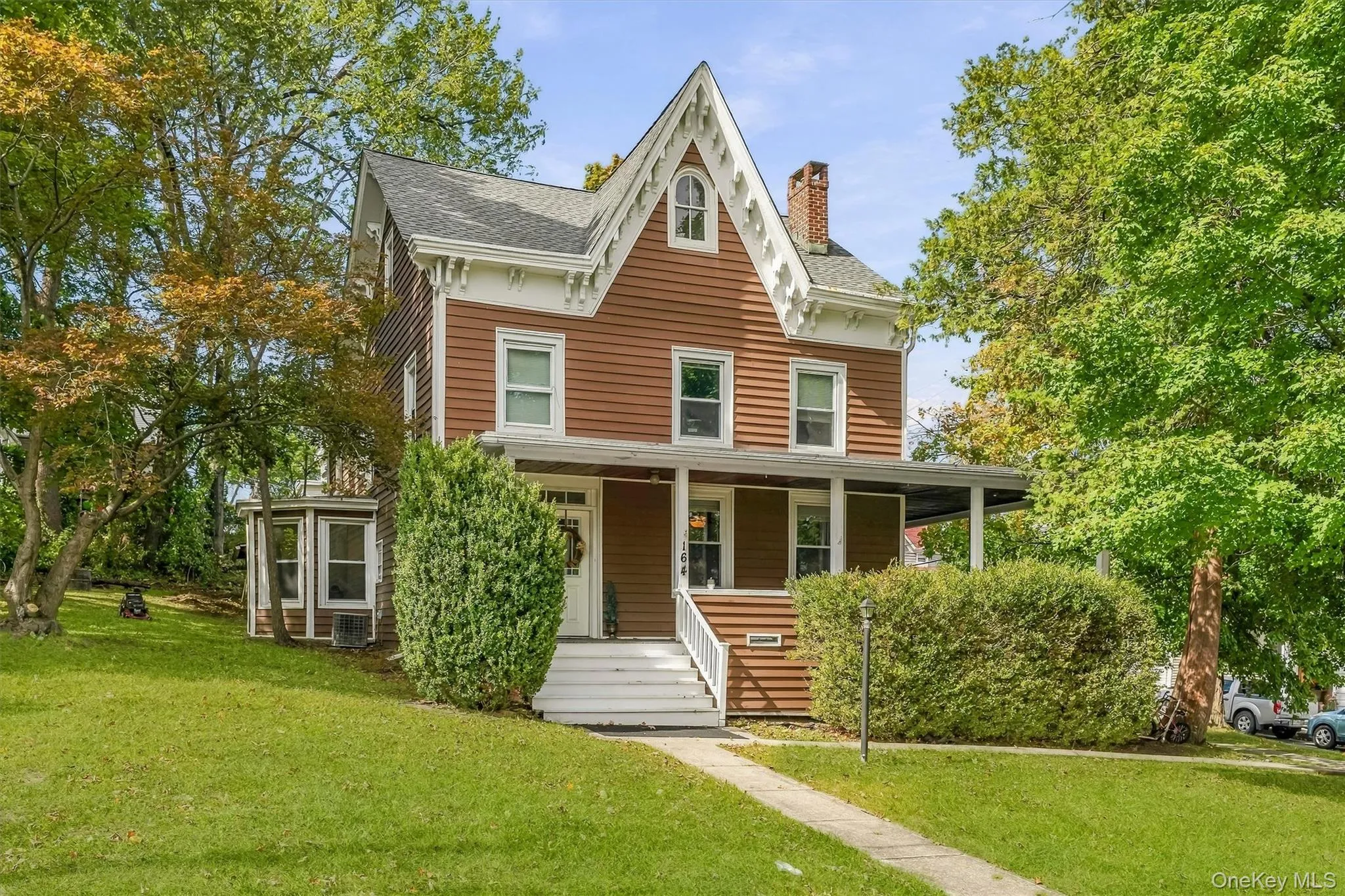 Victorian-style residence featuring brown siding with white trim, a covered front porch, and a prominent front gable Victorian-style residence featuring brown siding with white trim, a covered front porch, and a prominent front gable