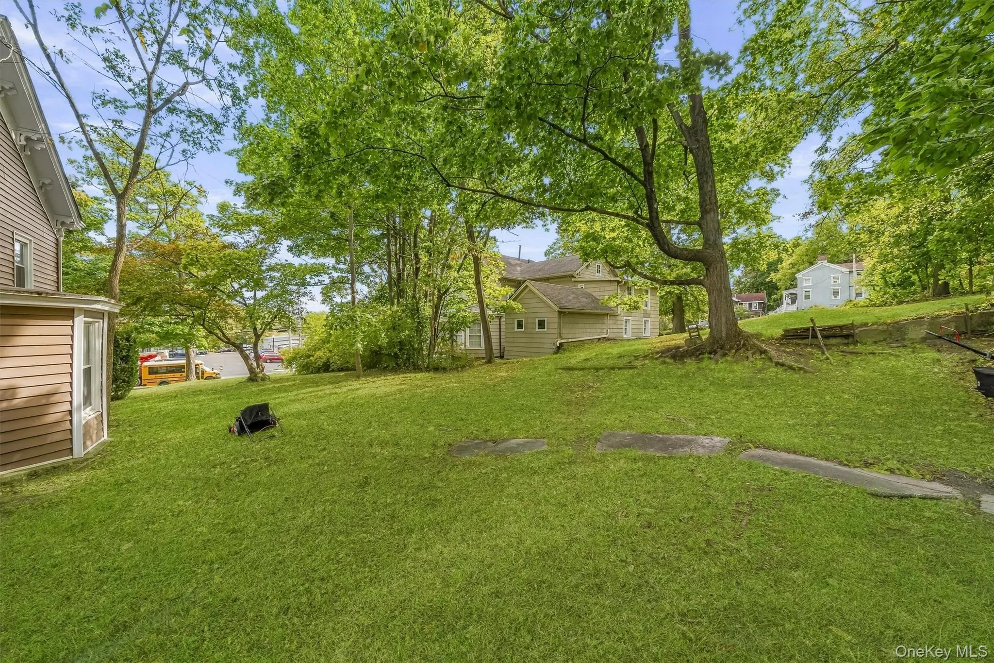 Expansive green lawn with mature trees and a side bay window on the residence Expansive green lawn with mature trees and a side bay window on the residence
